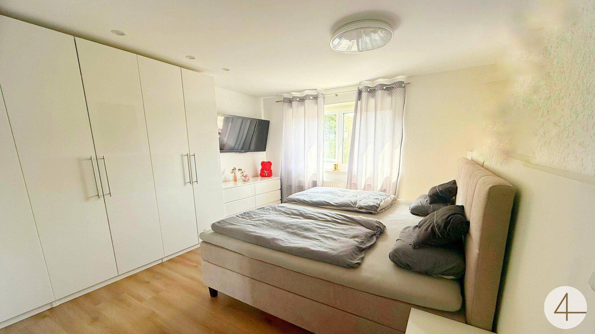 Schlafzimmer mit Doppelbett, großen weißen Kleiderschränken und hellem Laminatboden.