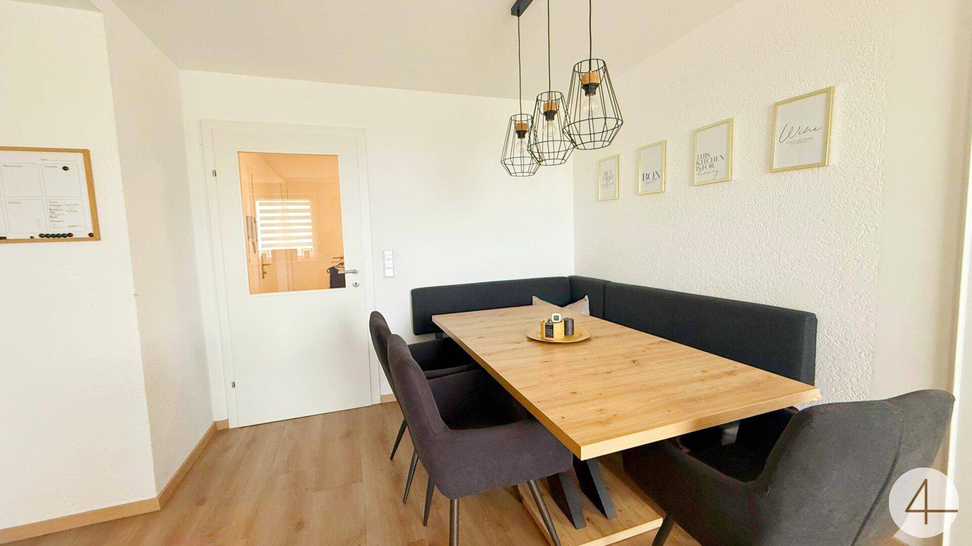 Gemütlicher Essbereich mit Holztisch, Eckbank und modernen Hängelampen.