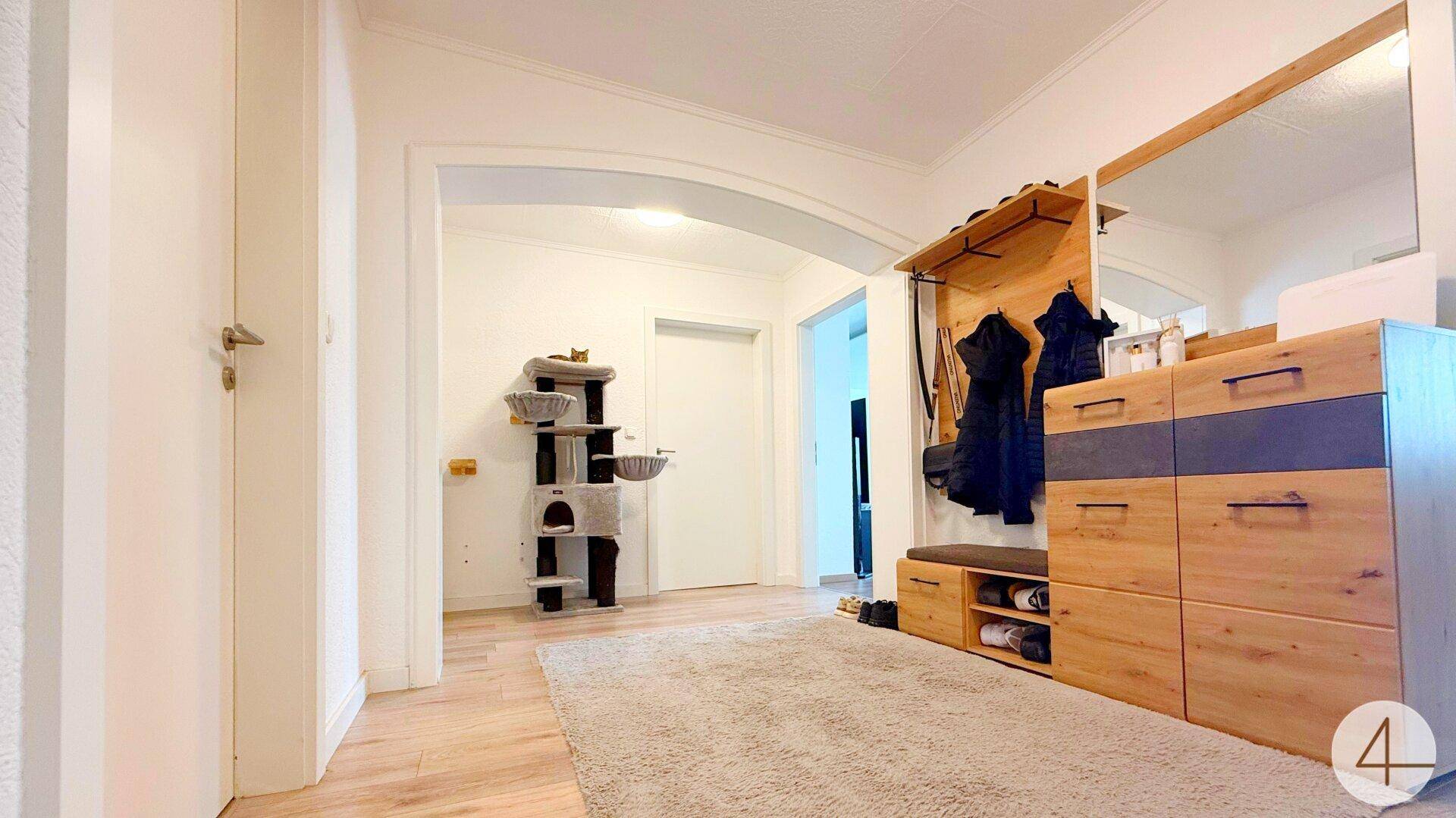 Geräumiger Flur mit Holzmöbeln, einem Katzenbaum und hellem Laminatboden.