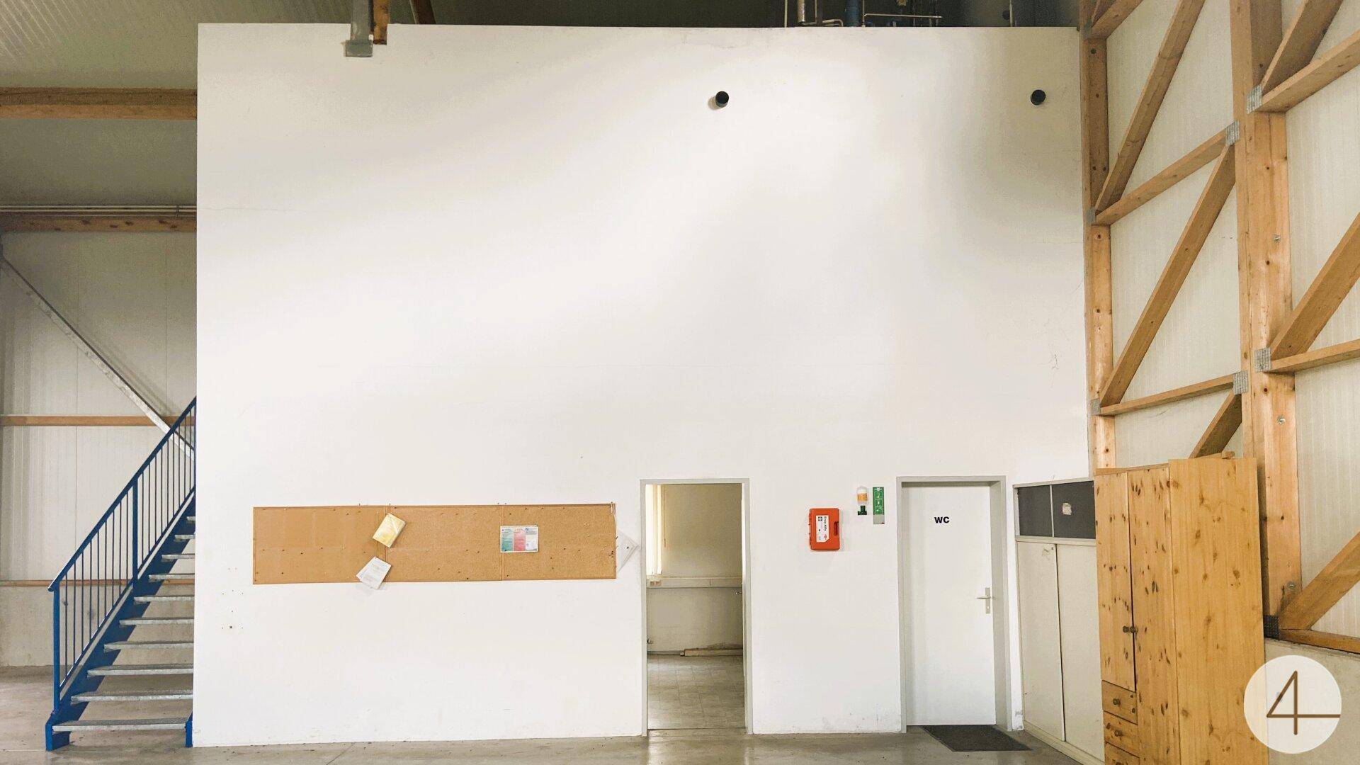 Innenbereich mit weißer Wand, zwei Türen, einer Pinnwand und einer blauen Stahltreppe.