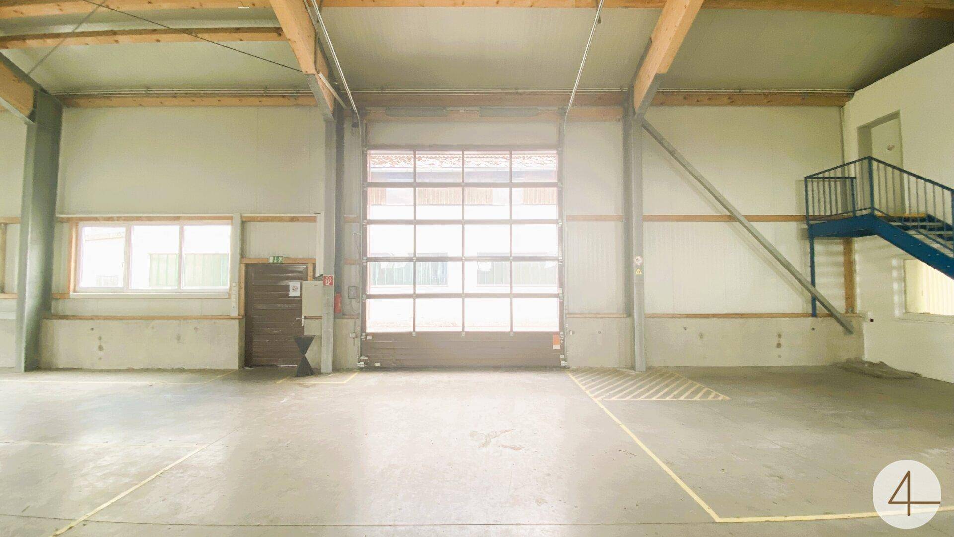 Geräumige Lagerhalle mit großem Rolltor, Fenstern und Betonboden, bereit zur Nutzung.