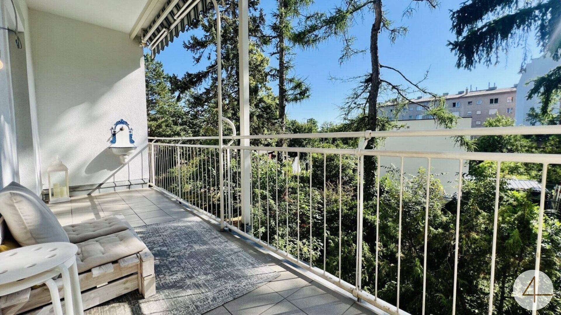 Geräumiger Balkon mit Fliesenboden, dekorativem Wandbrunnen und üppigem Grünblick.