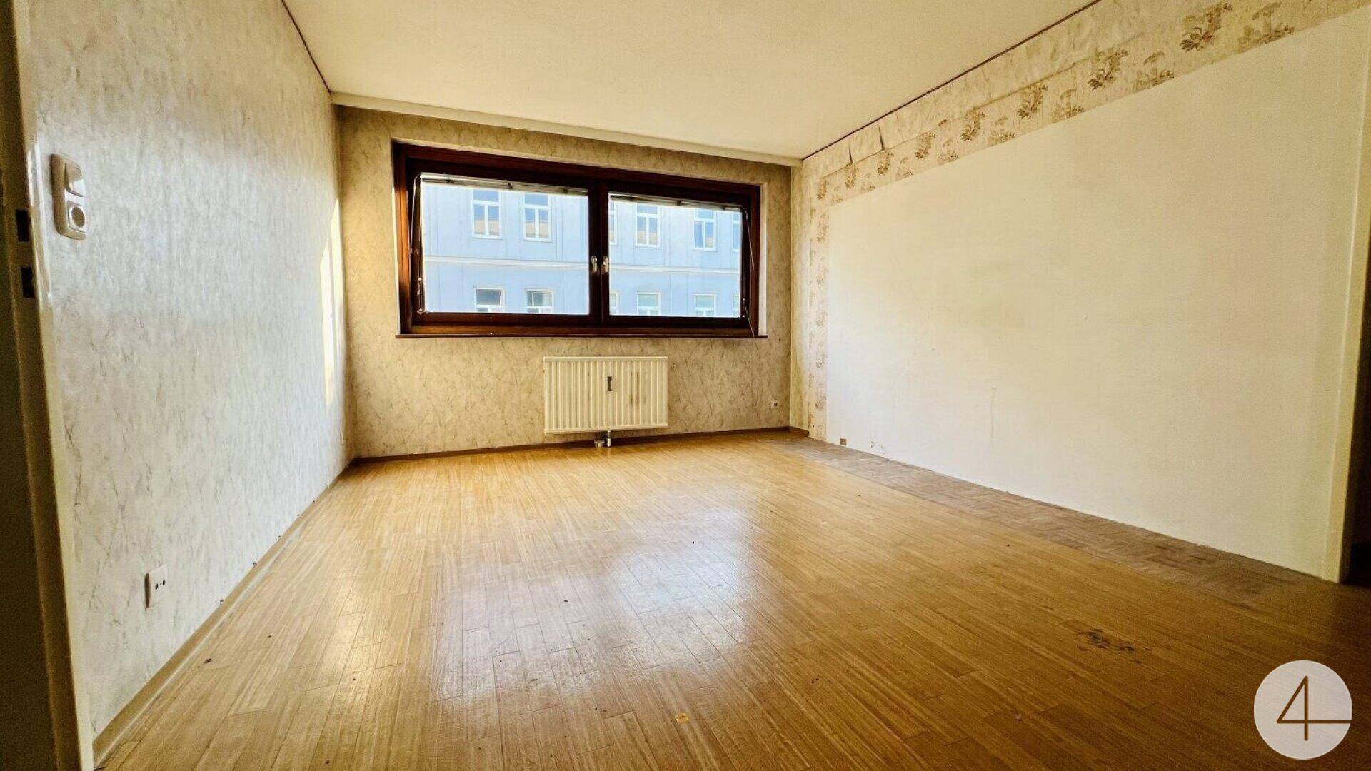 Unmöbliertes Zimmer mit Holzboden und Fenster, das auf eine Renovierung wartet.