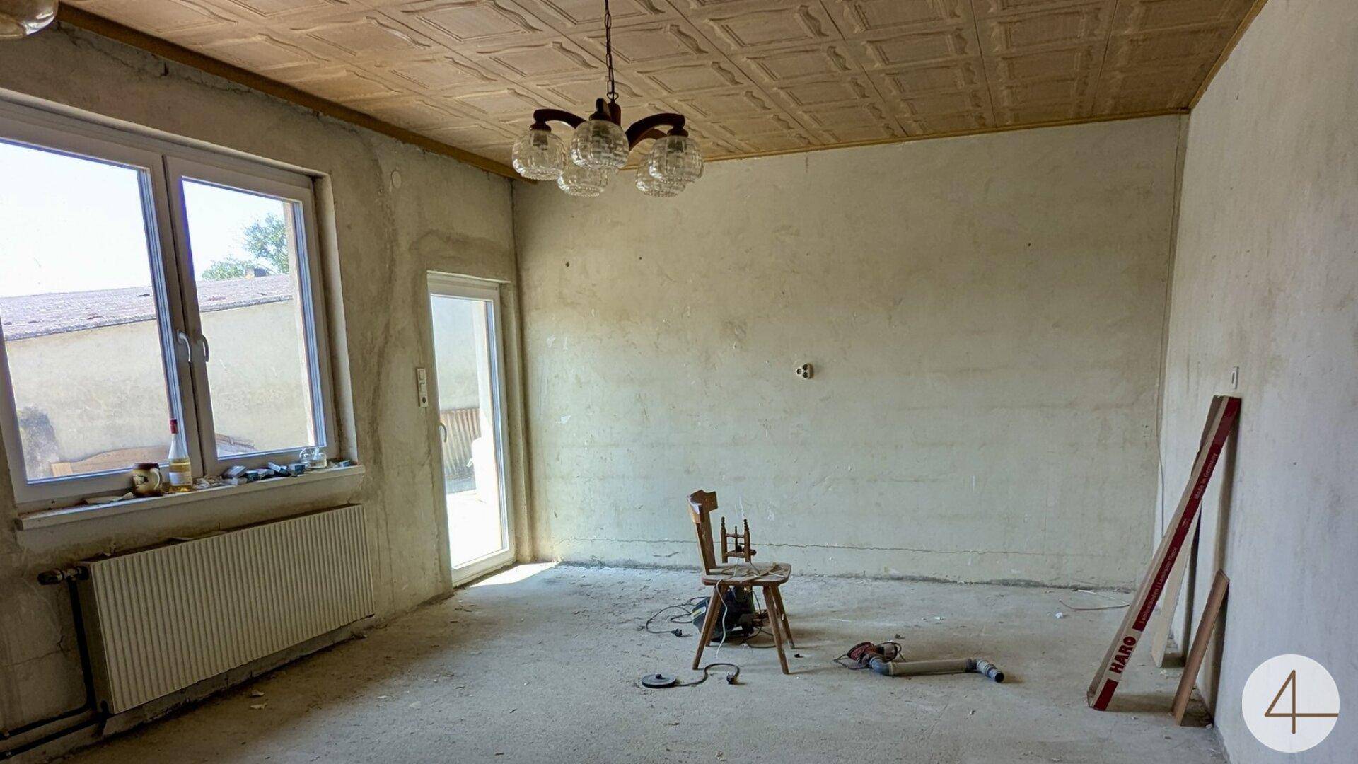 Unrenovierter Innenraum mit kahlen Wänden, Betonboden und Fenster, bereit zur Neugestaltung.