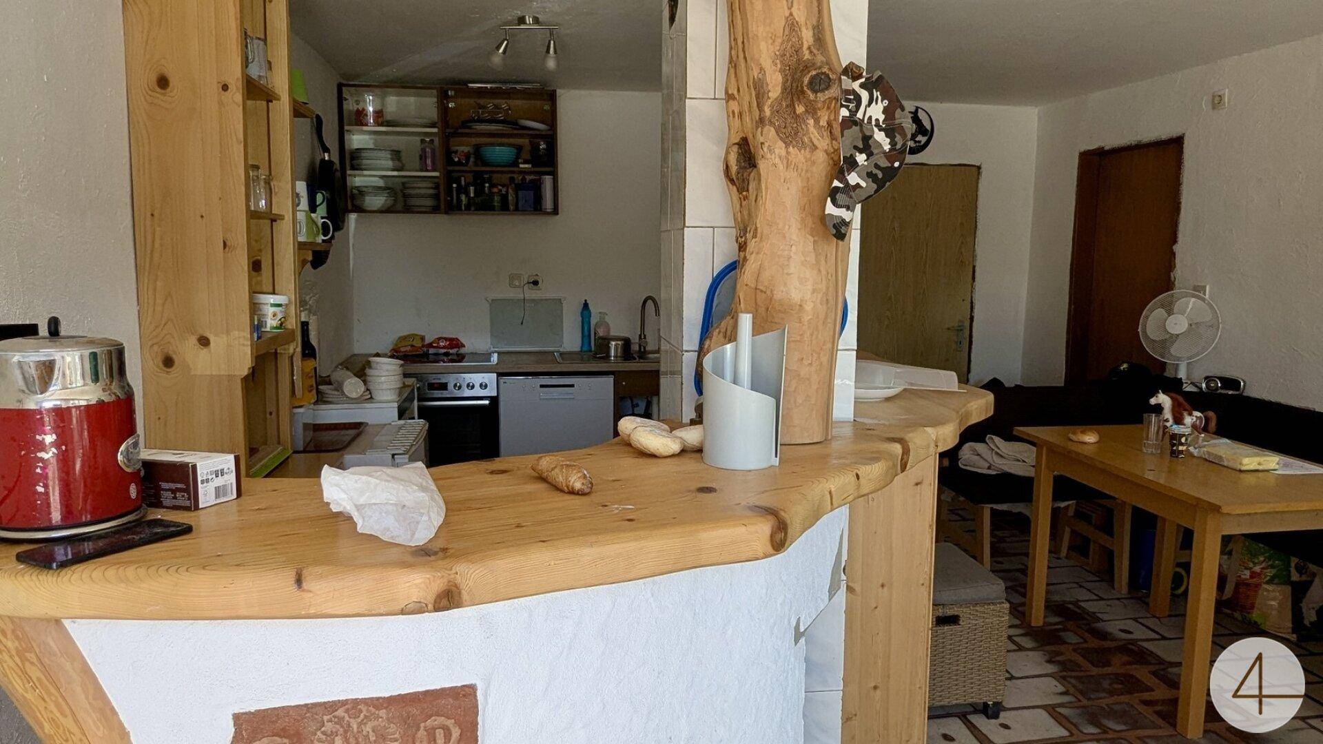 Rustikale Küche mit Holzbartheke und Essbereich, ausgestattet mit einfachen Möbeln.