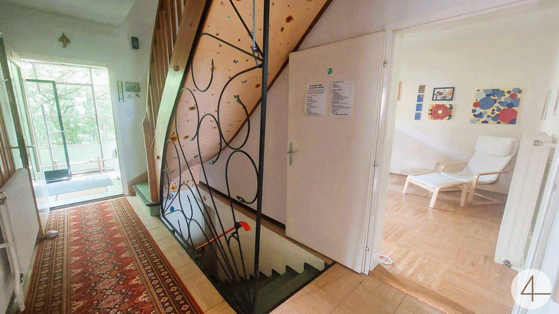 Geräumiger Flur mit Treppe ins Untergeschoss und Zugang zu einem hellen Wohnbereich.