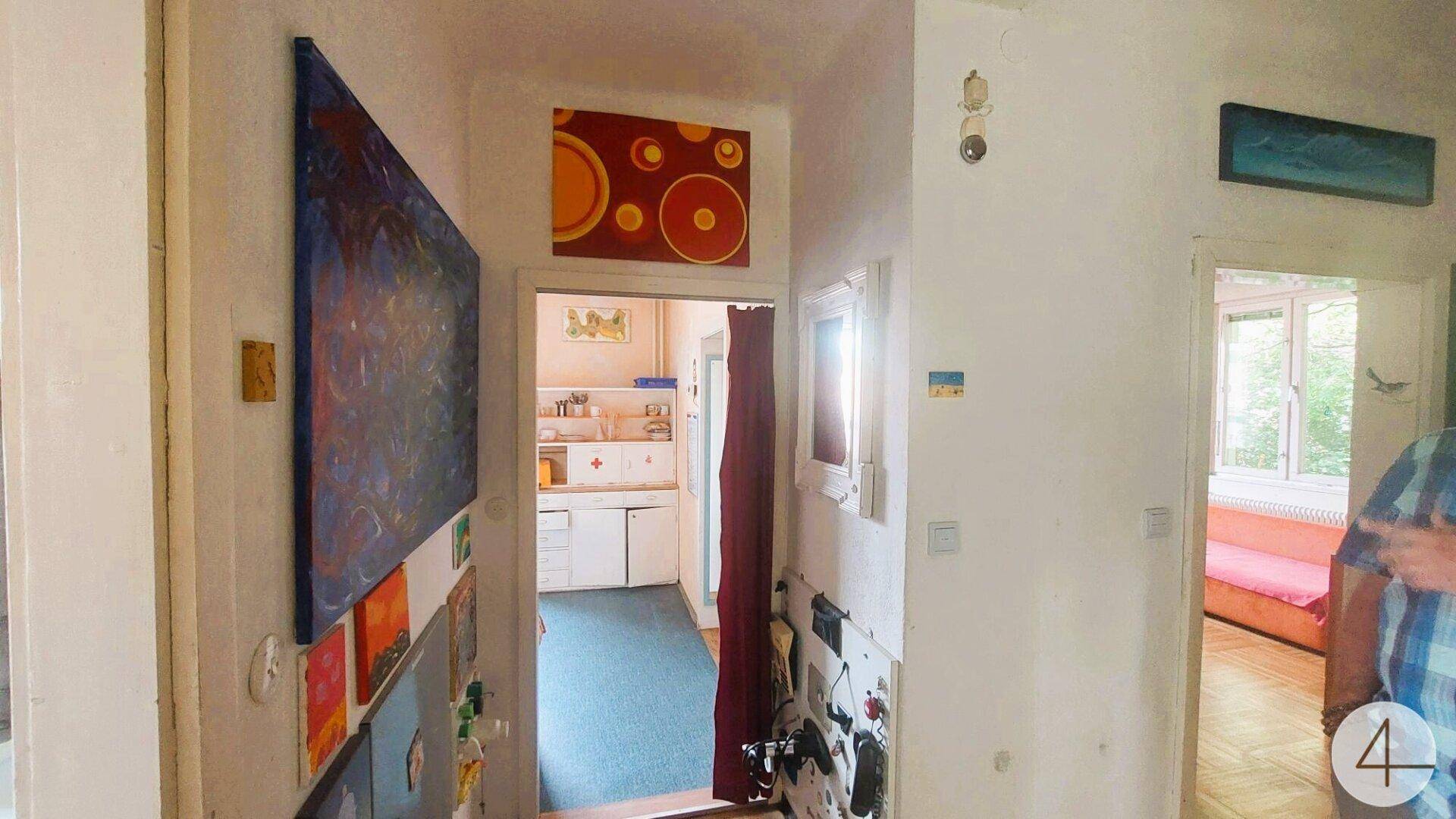 Flur mit farbenfrohen Kunstwerken an den Wänden und Zugang zu verschiedenen Räumen.