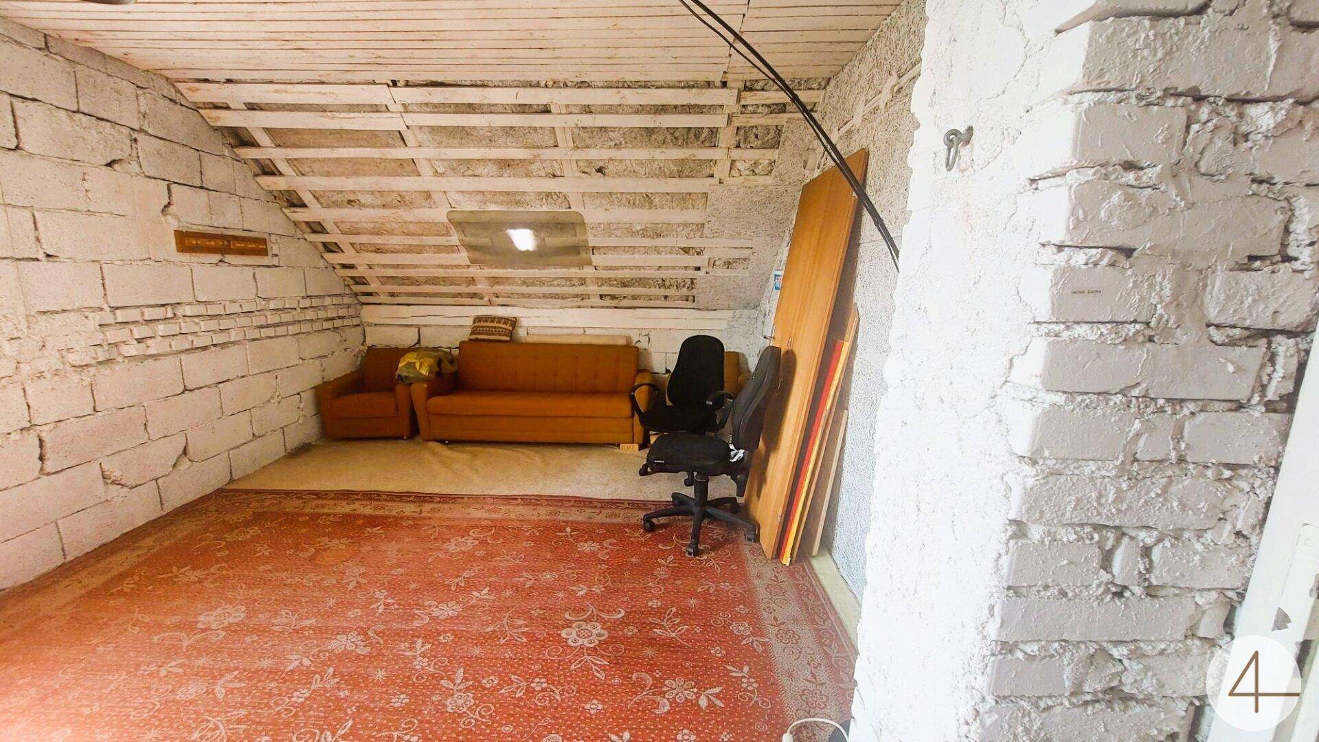 Geräumiger Dachbodenraum mit Sofa, Bürostuhl und Teppichboden, vielseitig nutzbar.