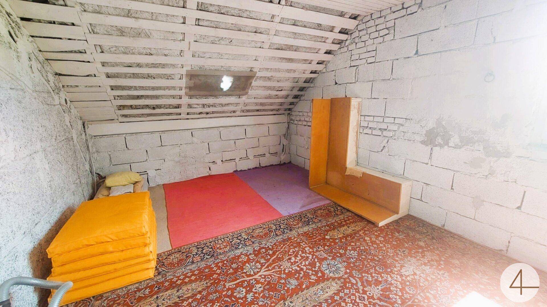 Dachbodenraum mit unverputzten Ziegelwänden, schräger Decke und Teppichboden.