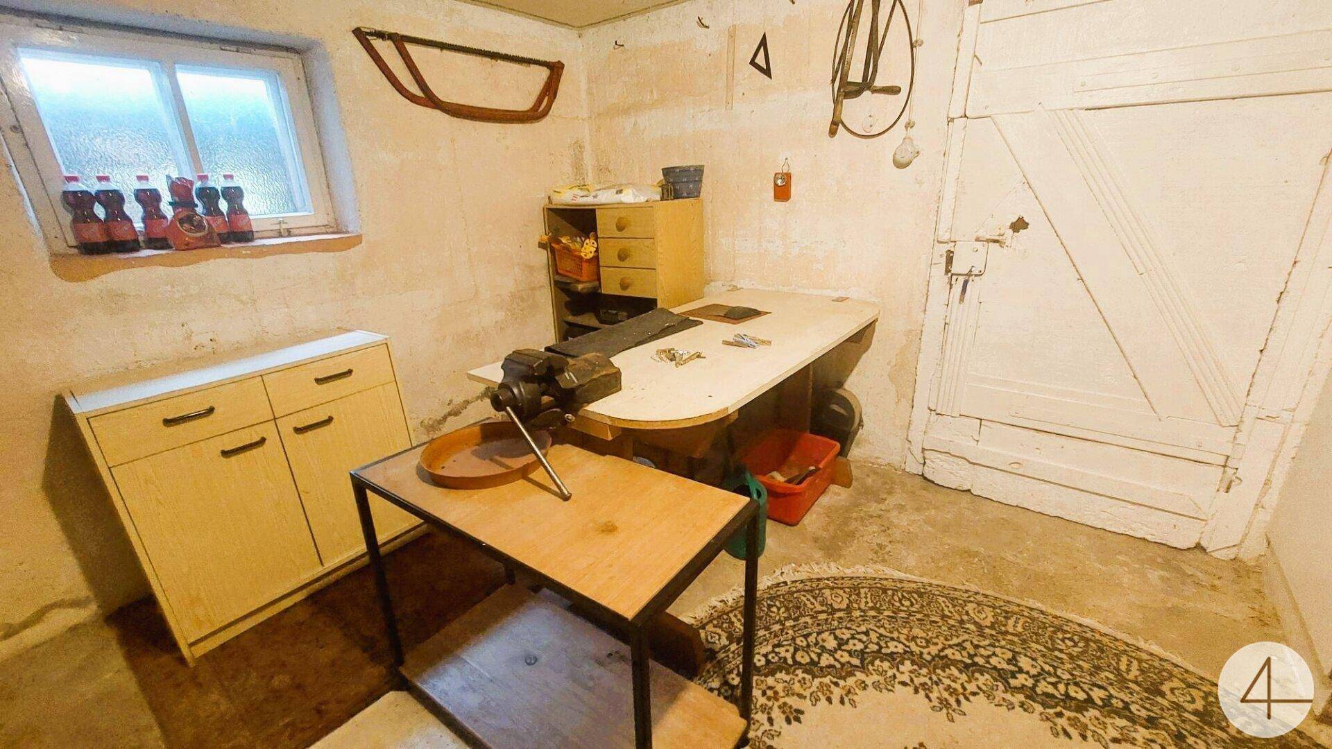Werkstatt im Keller mit Werkbank, Schraubstock und verschiedenen Werkzeugen, funktional eingerichtet.