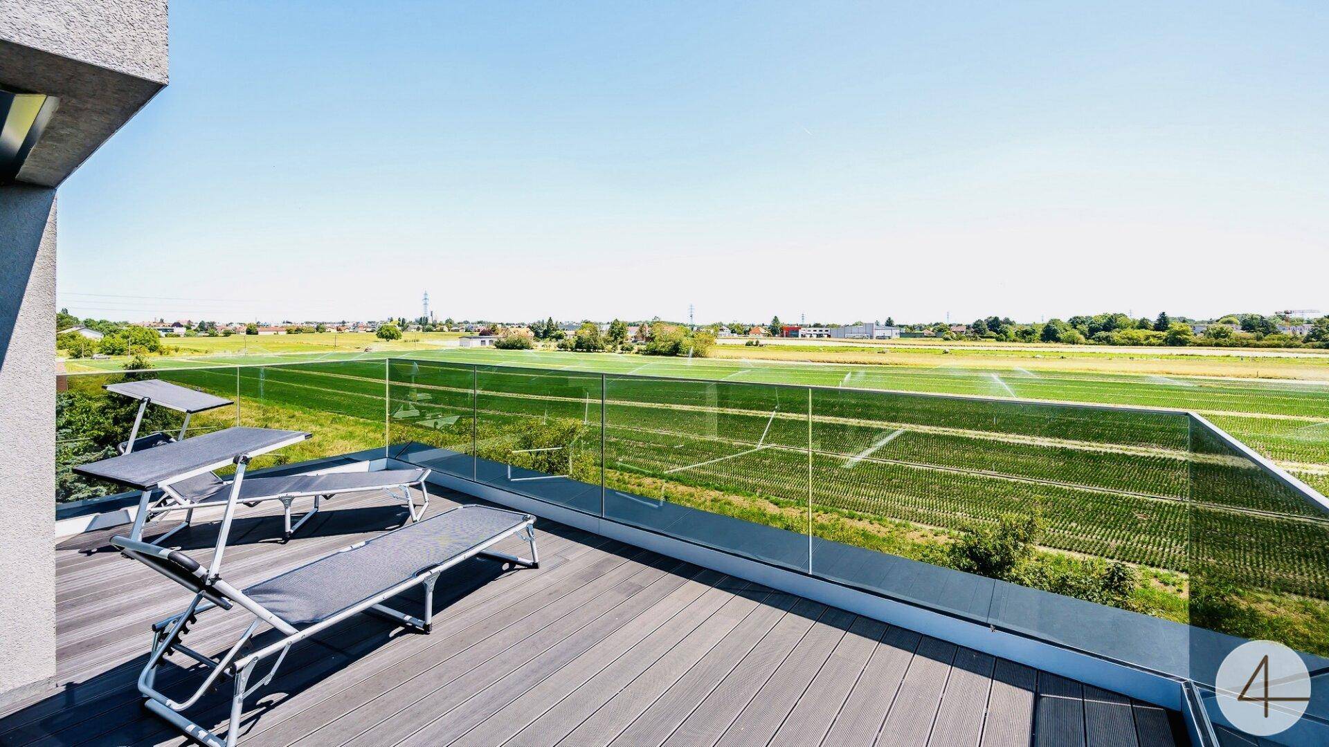 Geräumige Dachterrasse mit Liegestühlen und weitem Blick über grüne Felder und die Landschaft.