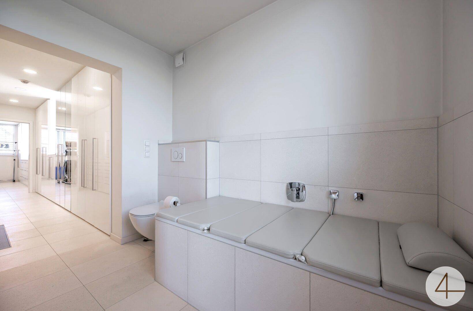 Modernes Badezimmer mit WC und einer gepolsterten Liegefläche, die zum Entspannen einlädt.