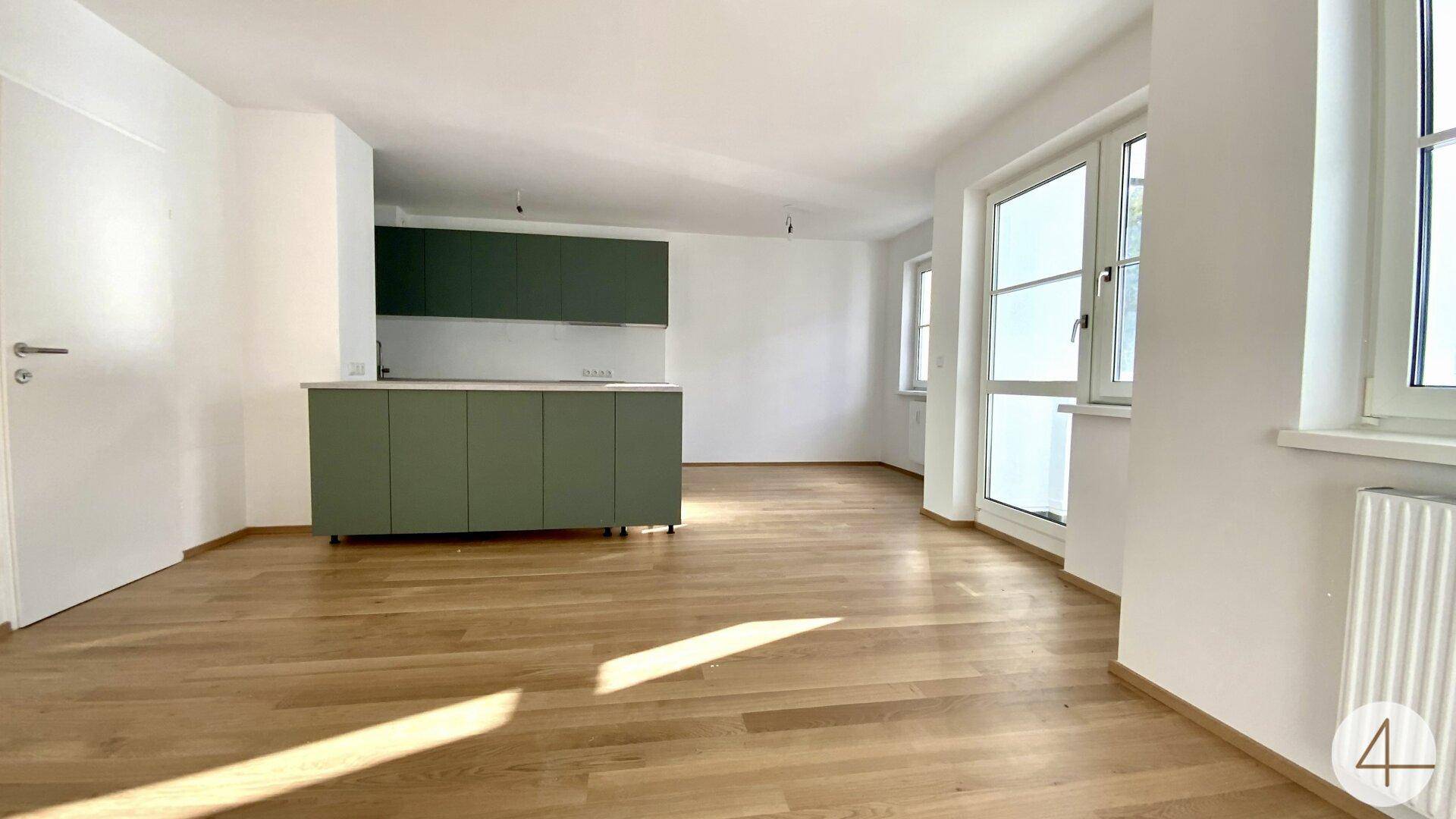 Geräumiger, offener Wohnbereich mit moderner Einbauküche und viel Tageslicht.