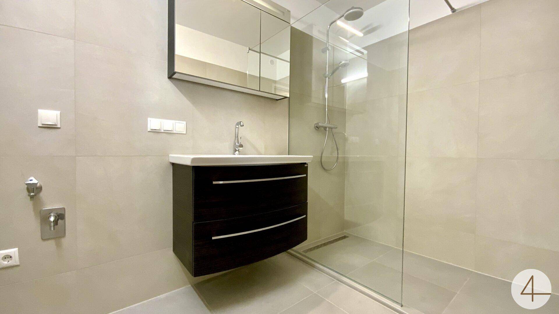 Modernes Badezimmer mit begehbarer Dusche, schwebendem Waschtisch und großformatigen Fliesen.