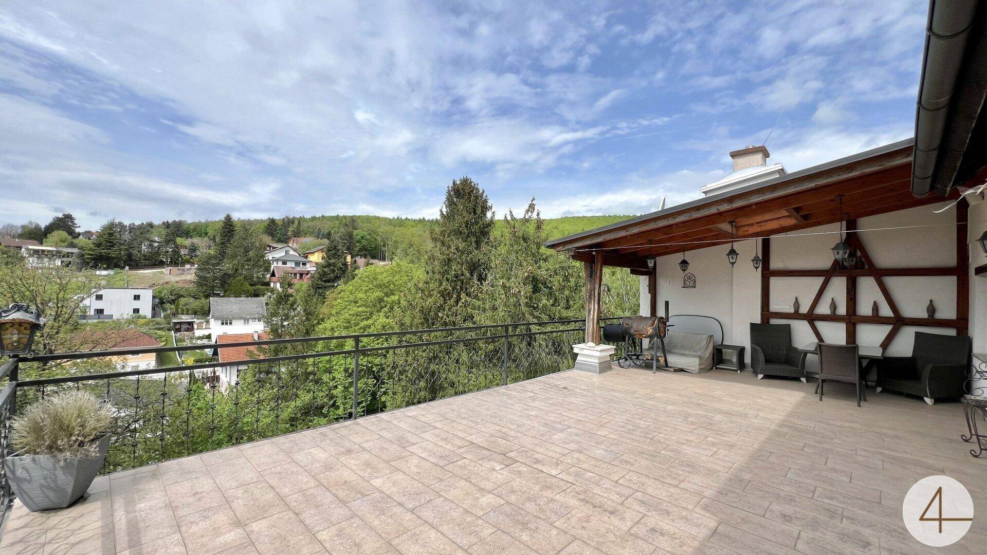 Weitläufige Terrasse mit Überdachung, Sitzgelegenheiten und Panoramablick auf die Landschaft.