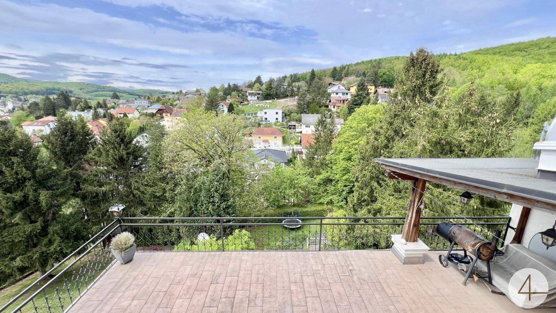 Geräumige Terrasse mit Panoramablick auf die bewaldeten Hügel und die darunter liegende Siedlung.