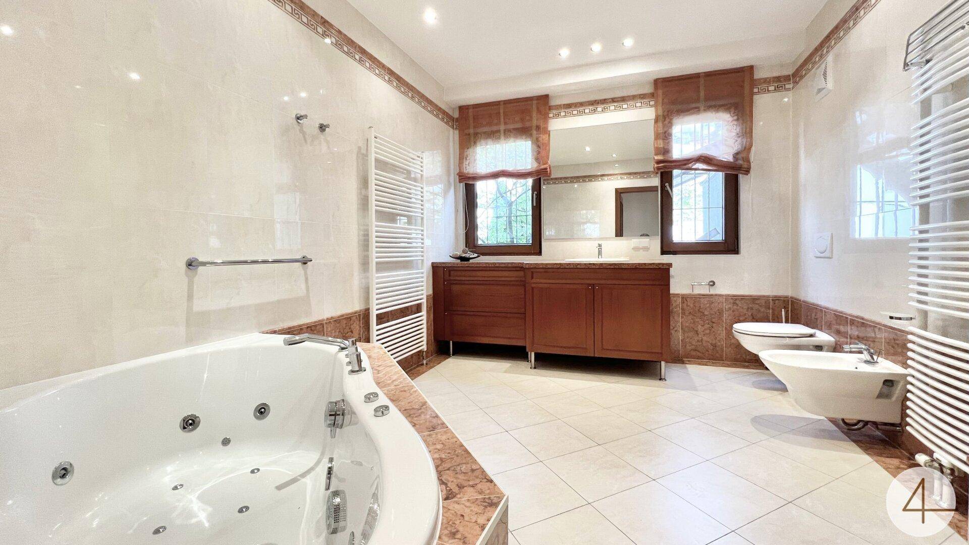 Luxuriöses Badezimmer mit Whirlpool, Doppelwaschbecken und beheiztem Handtuchhalter.