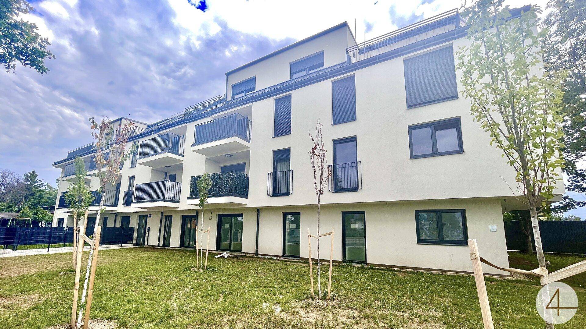 Modernes Mehrfamilienhaus mit Balkonen, großen Fenstern und gepflegten Grünflächen im Außenbereich.