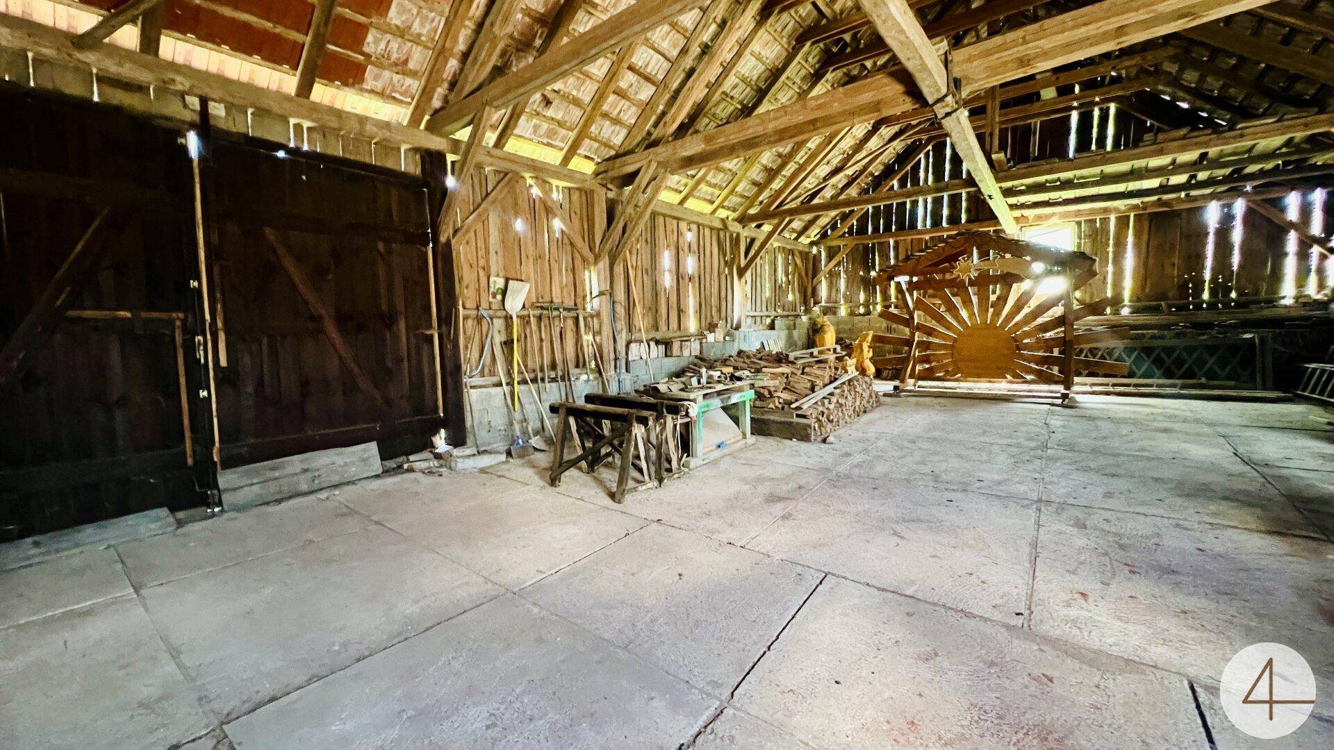 Geräumige Scheune mit sichtbaren Holzbalken, Werkzeugen und viel natürlichem Licht.