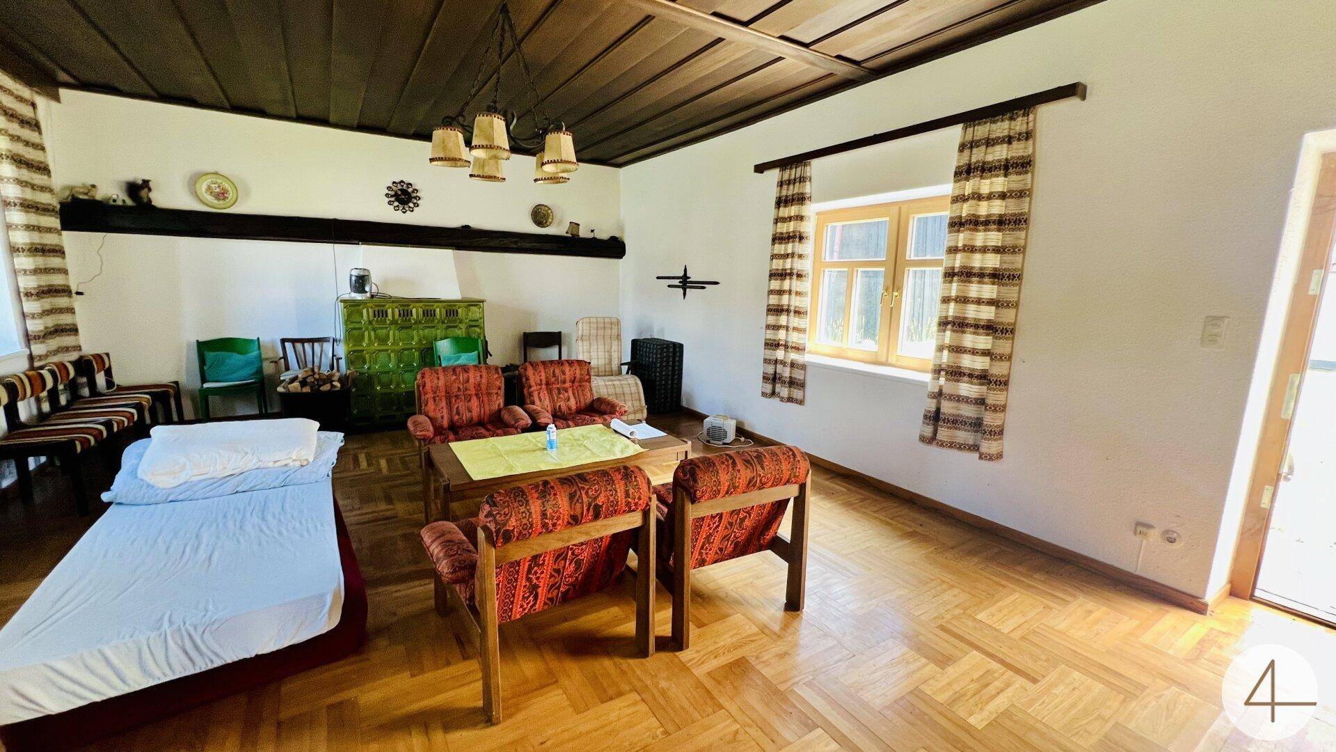 Gemütliches Wohnzimmer im traditionellen Stil mit Kachelofen, Holzboden und rustikalen Möbeln.