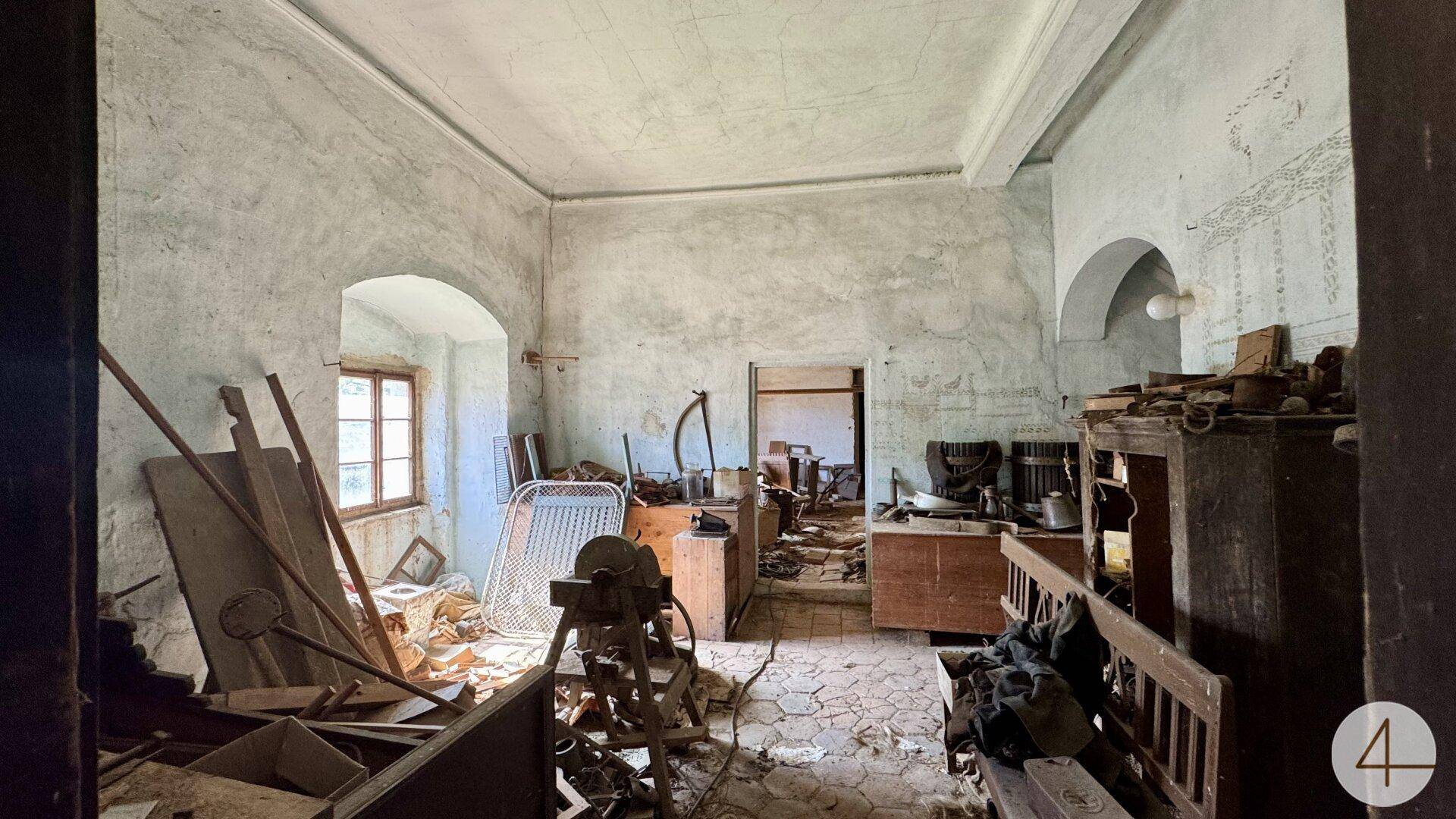 Großer, leerstehender Raum mit Putzschäden, alten Geräten und einem Fenster, das auf Renovierung wartet.
