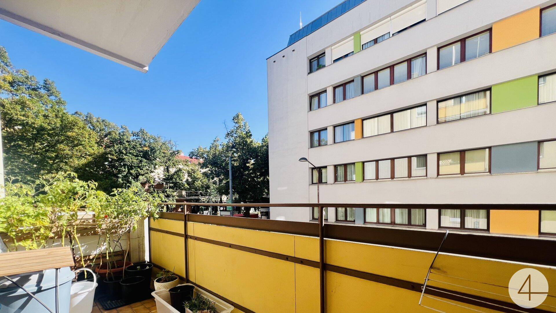 Sonniger Balkon mit Pflanzen und Blick auf die umliegenden Gebäude und Bäume.