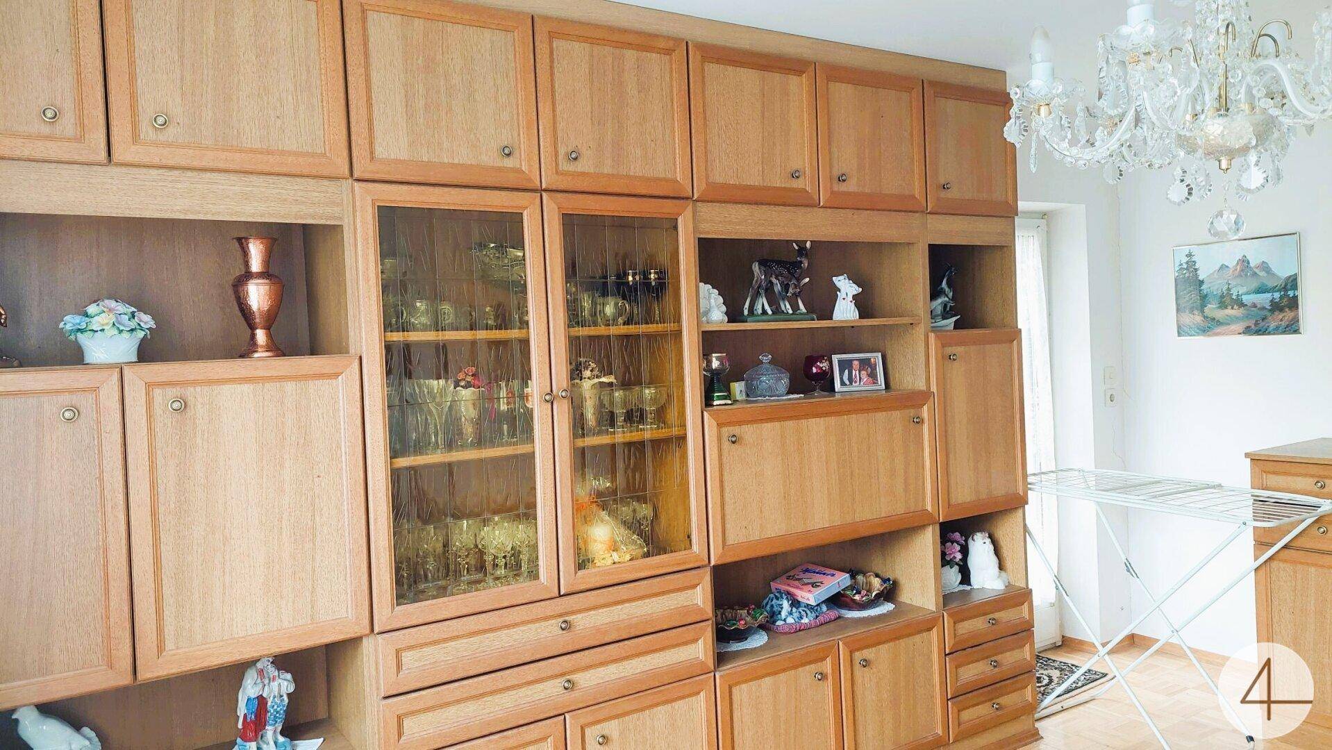 Detailansicht der traditionellen Holzschrankwand mit Glasvitrinen und Dekoration.