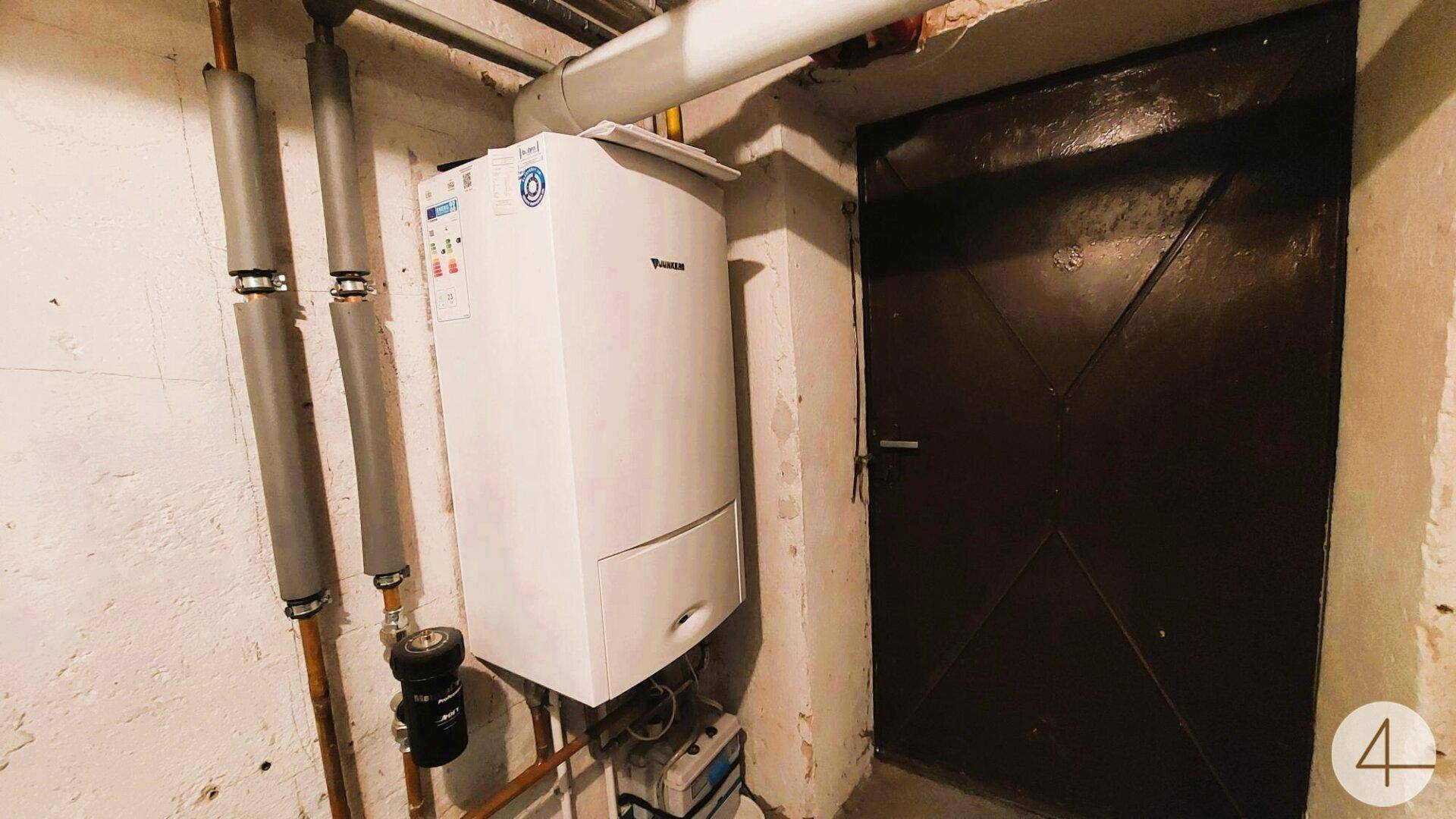 Heizraum mit einem modernen Heizsystem und isolierten Rohren an der Wand.
