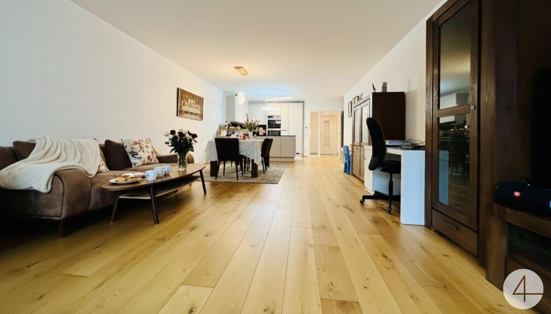 Geräumiger Wohnbereich mit hellem Holzboden, bequemer Couch und integriertem Essbereich.