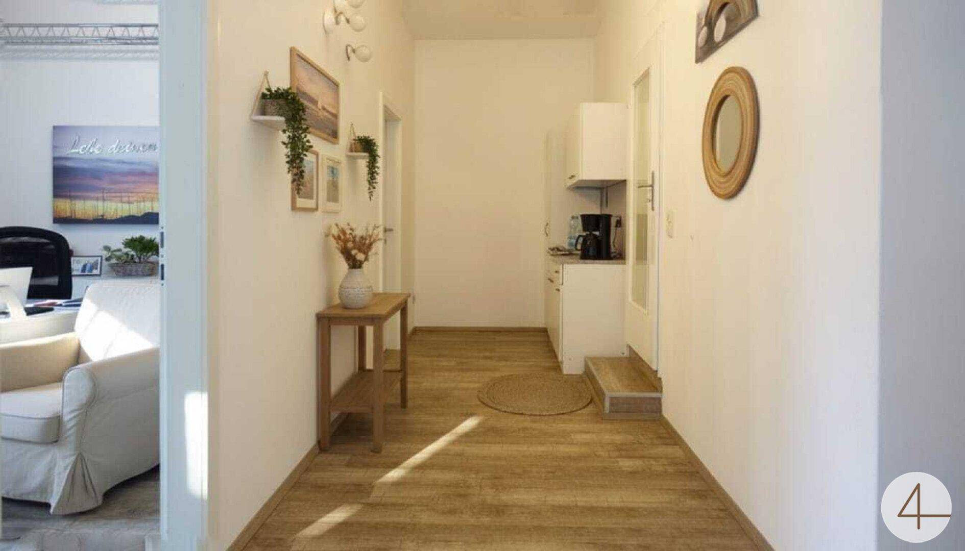 Heller Flur mit Holzoptikboden, minimalistischer Dekoration und Zugang zu weiteren Räumen.