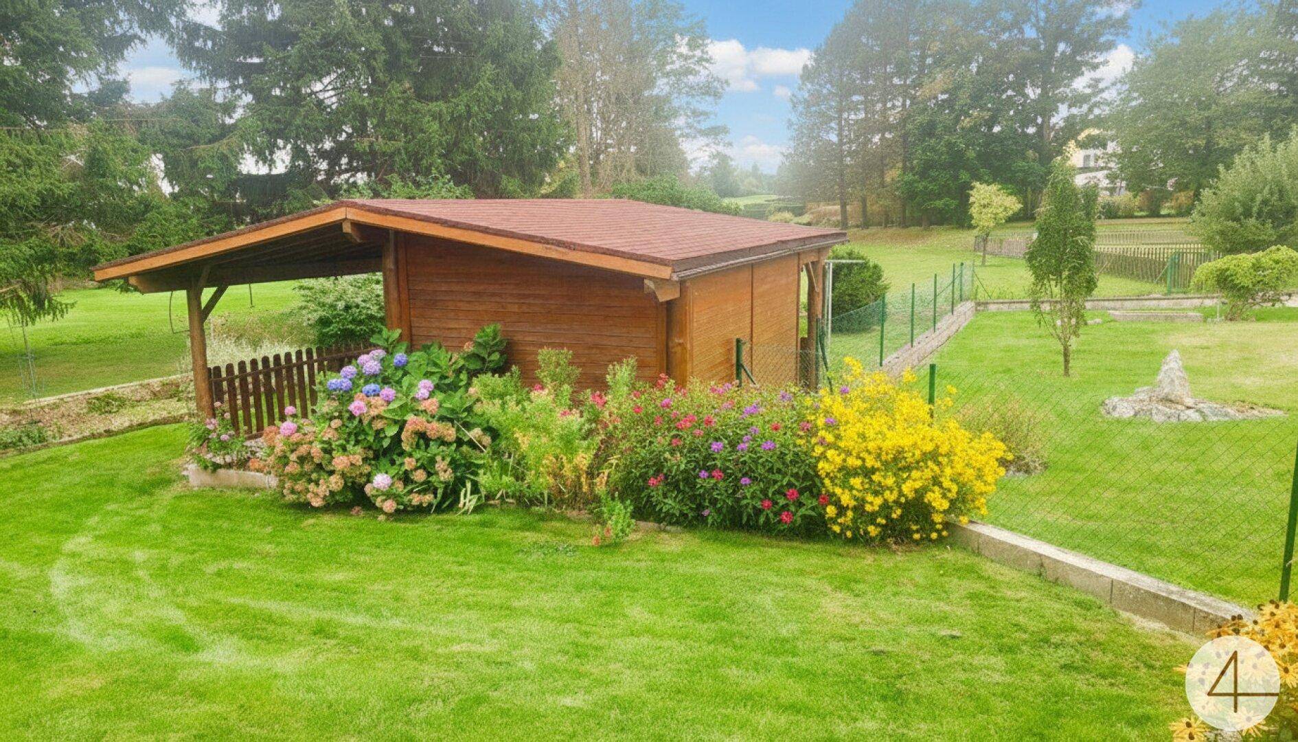 Holzgartenhaus mit kleiner überdachter Terrasse, umgeben von gepflegtem Rasen und bunten Blumenbeeten.