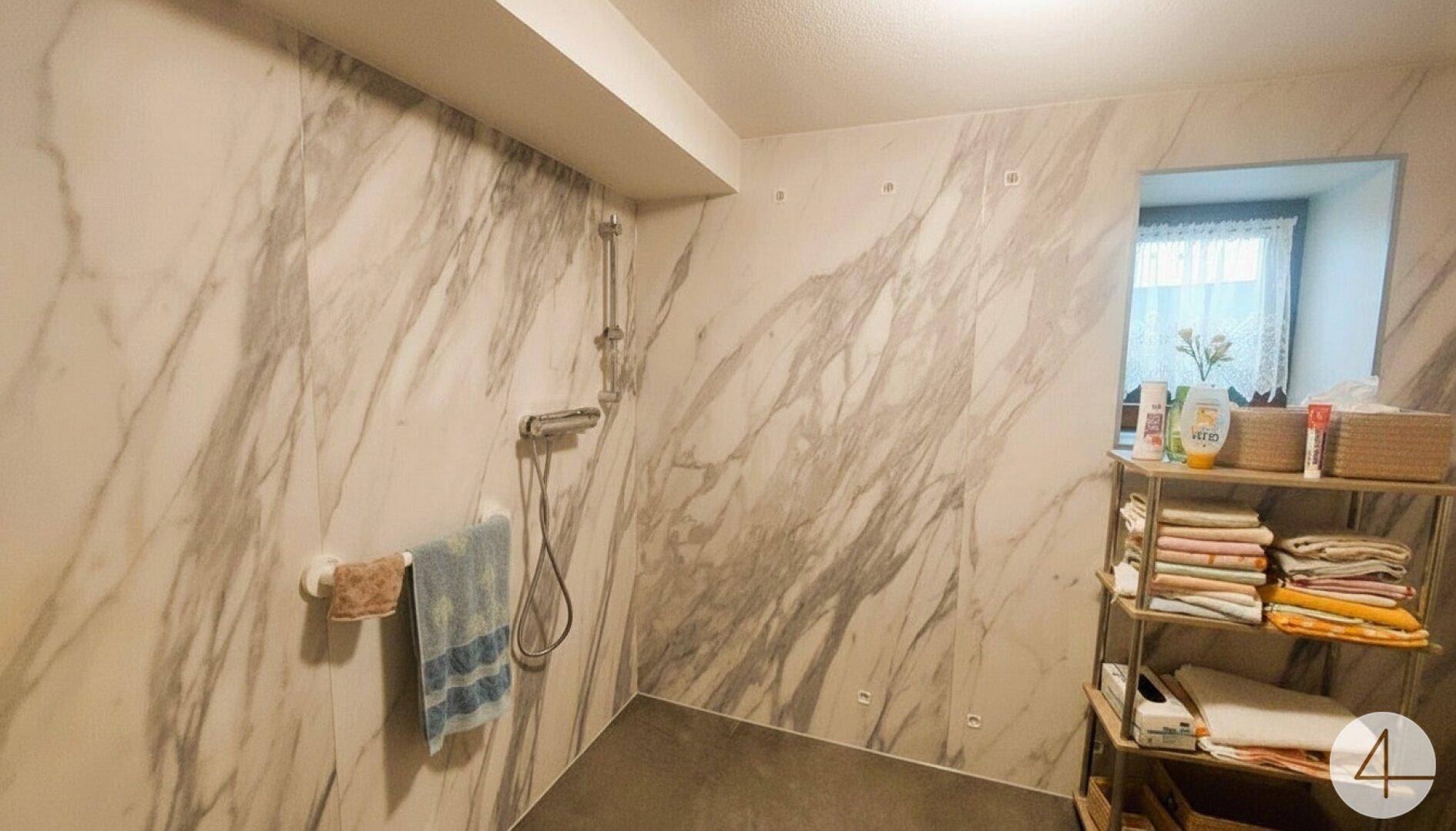 Modernes Duschbad mit großformatigen Marmorfliesen und ebenerdiger Dusche, sehr stilvoll.