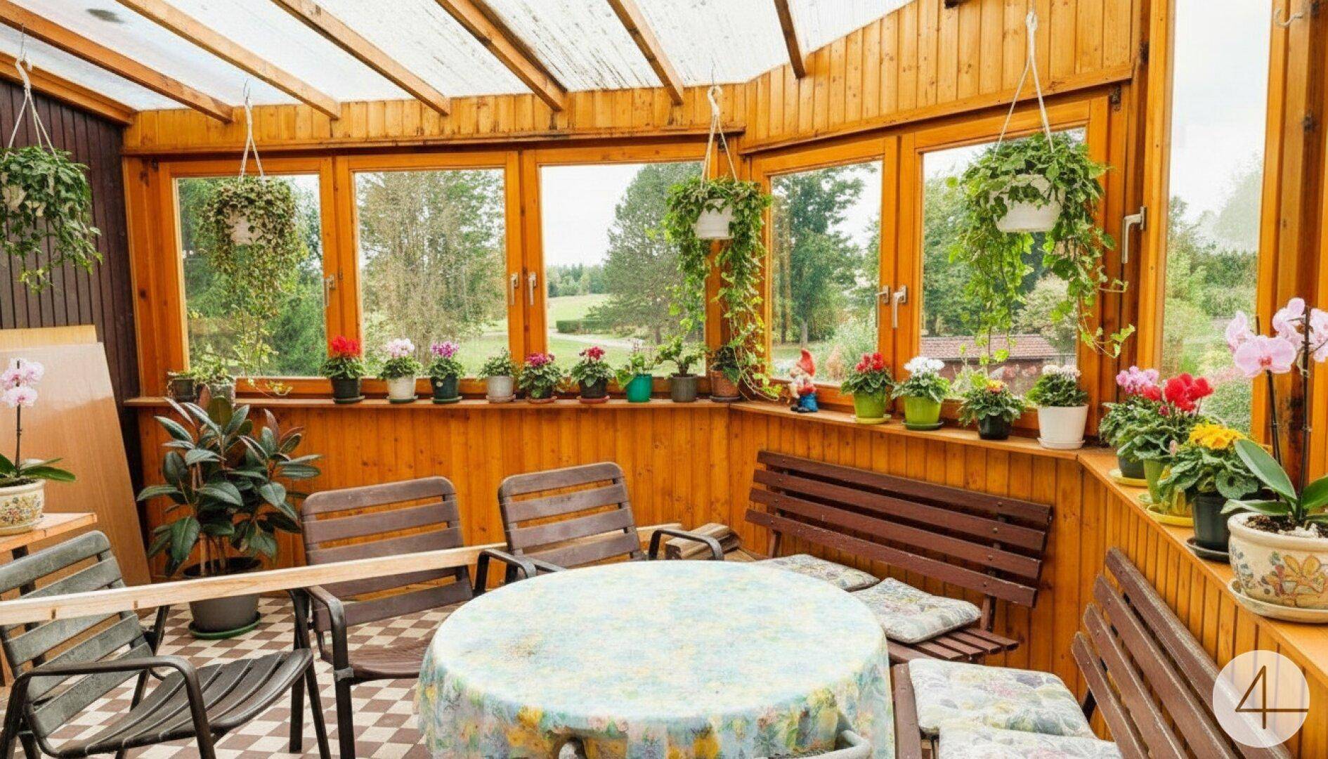 Heller Wintergarten mit Holzverkleidung, vielen Pflanzen und weitem Blick in die Natur.