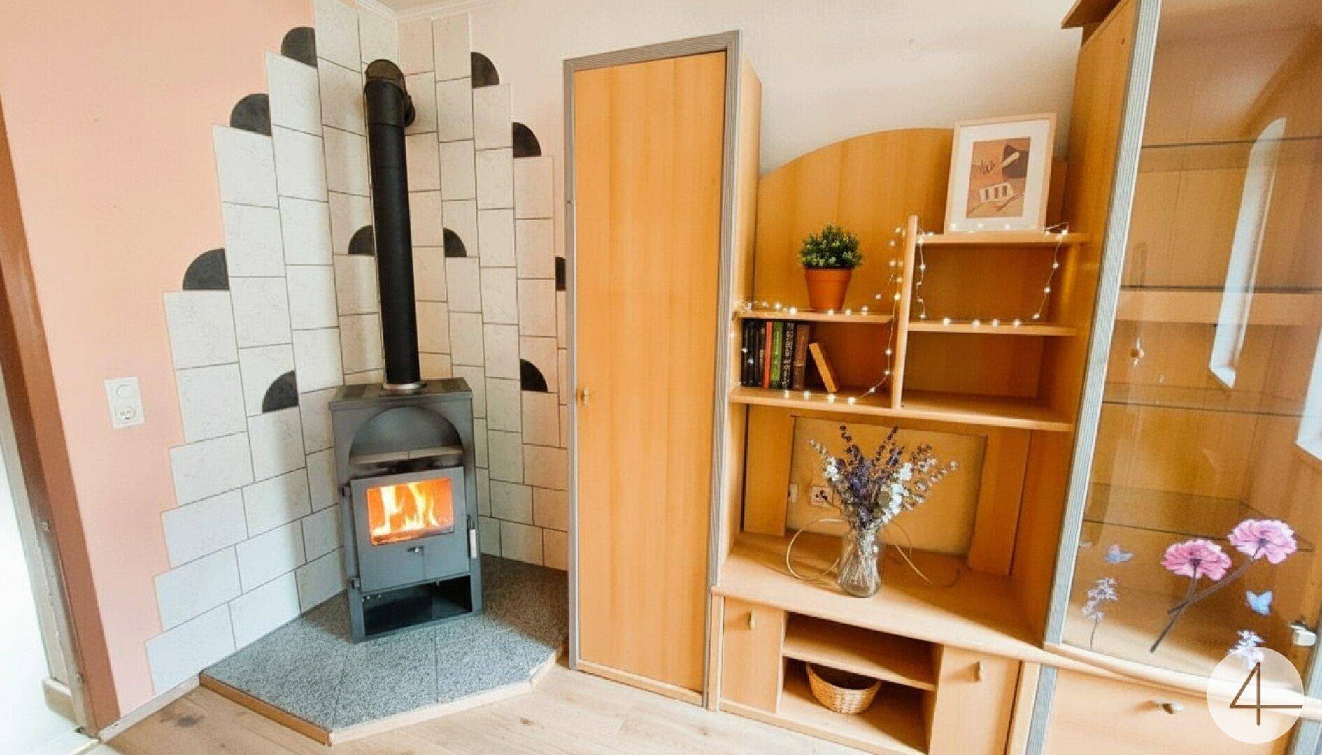 Gemütlicher Wohnbereich mit modernem Holzofen und Holzmöbeln, ideal für kalte Tage.
