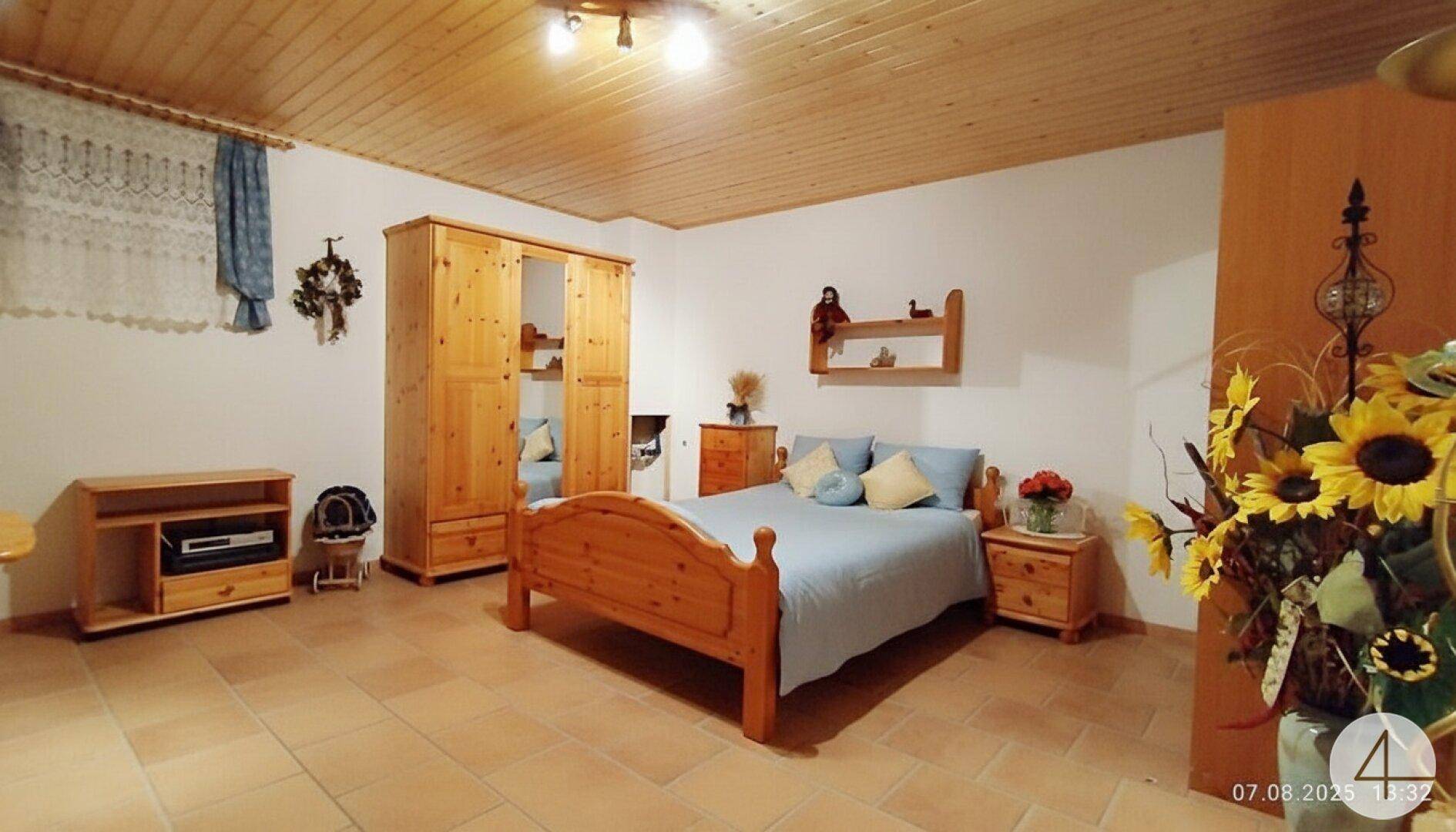 Gemütliches Schlafzimmer im Landhausstil mit Holzmöbeln und Terrakottafliesen.