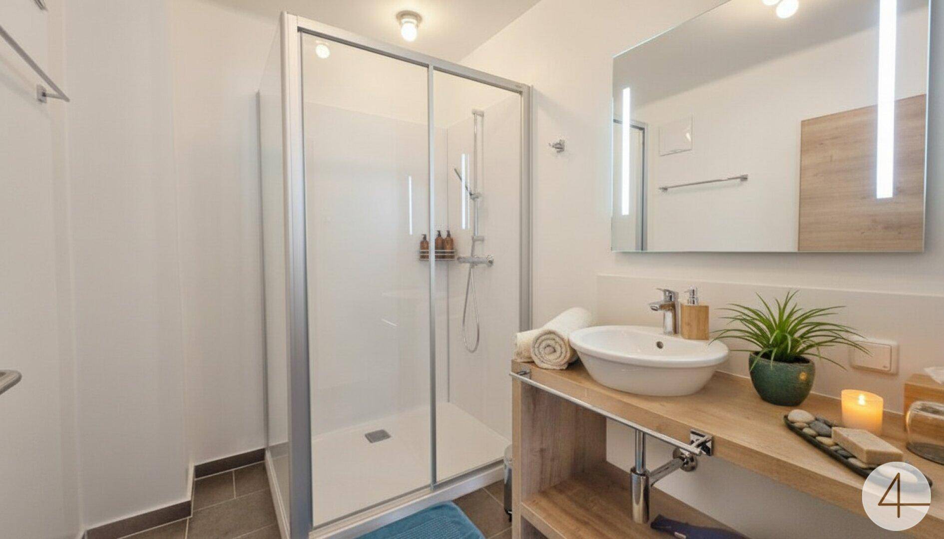 Modernes Badezimmer mit ebenerdiger Dusche, Einzelwaschbecken und beleuchtetem Spiegel.