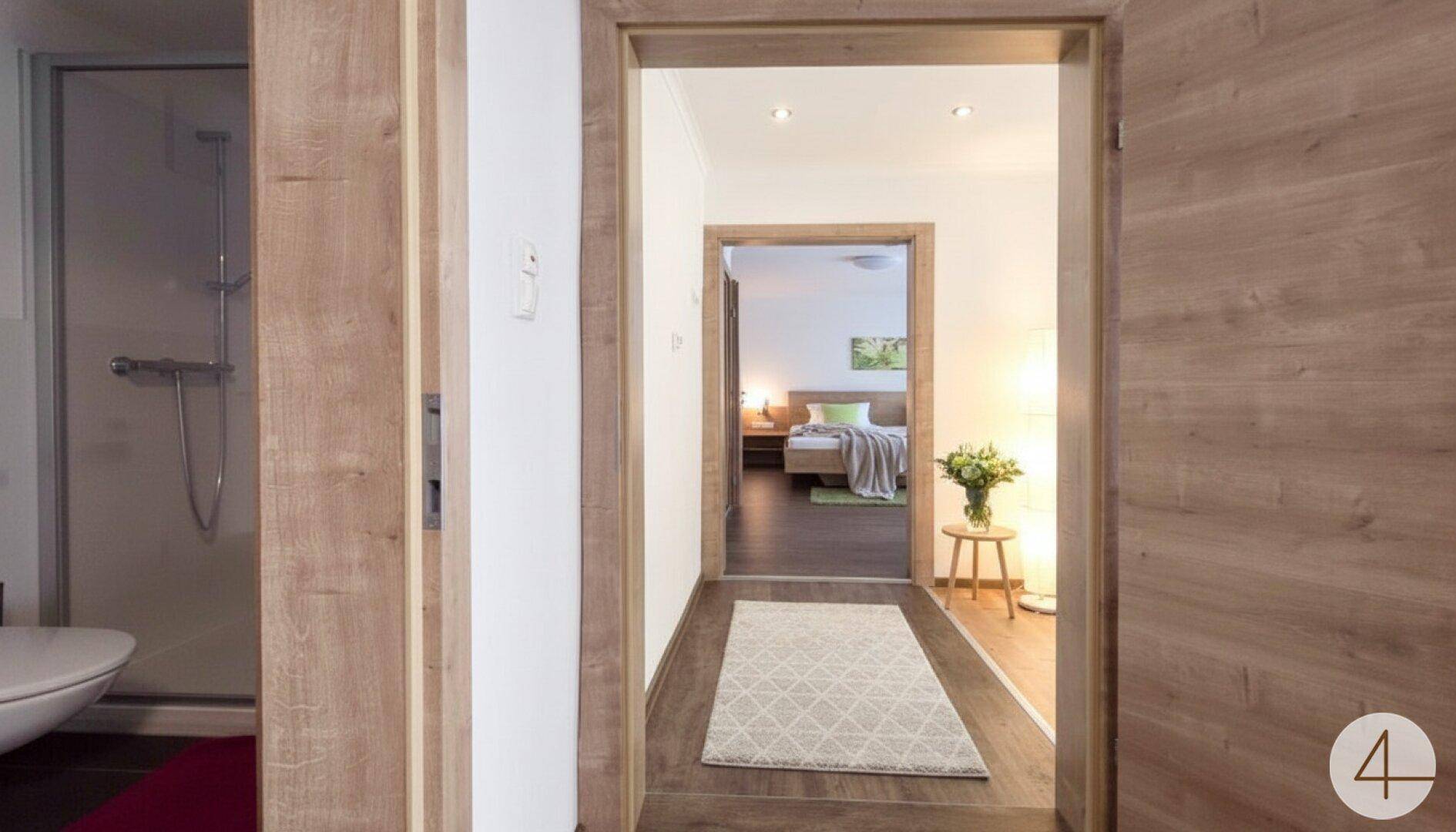 Flur mit Holztüren, der zu einem Schlafzimmer und einem Badezimmer führt.