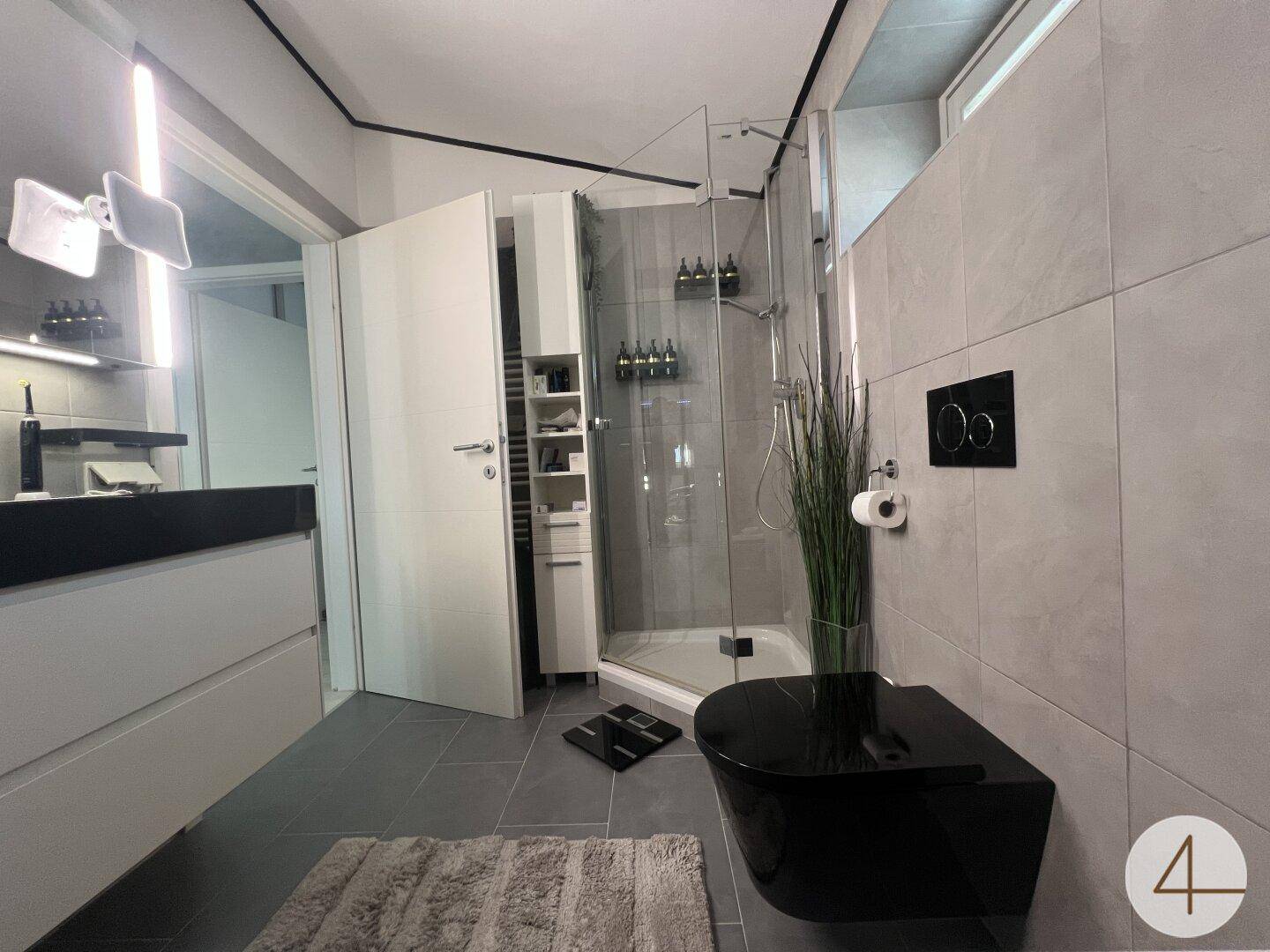 Helles Badezimmer mit großer Duschkabine, modernem Waschtisch und Wand-WC.