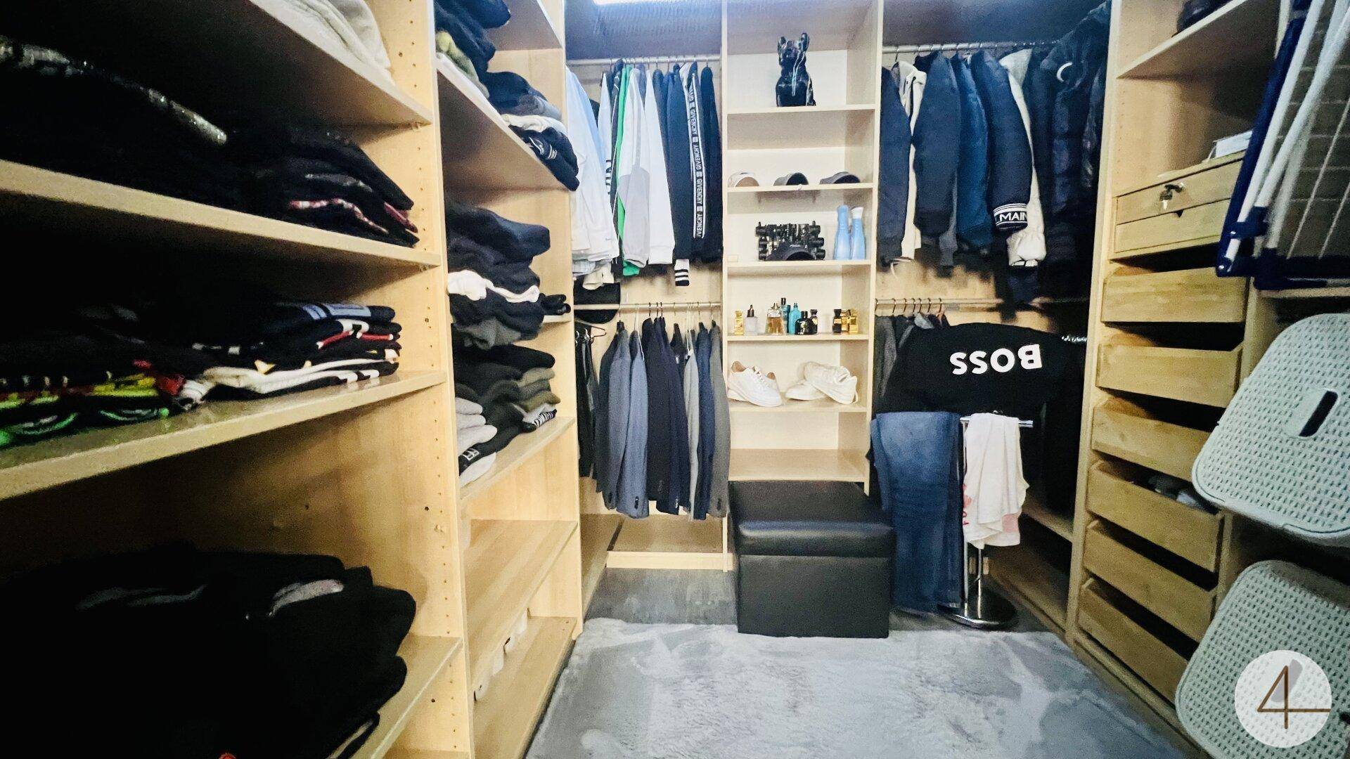Geräumiger begehbarer Kleiderschrank mit vielen Regalen, Schubladen und Kleiderstangen für Organisation.