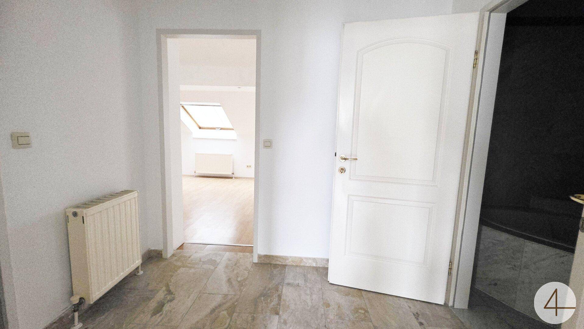 Heller Flur mit Fliesenboden und Zugang zu weiteren Räumen, inklusive einem Raum mit Dachfenster.