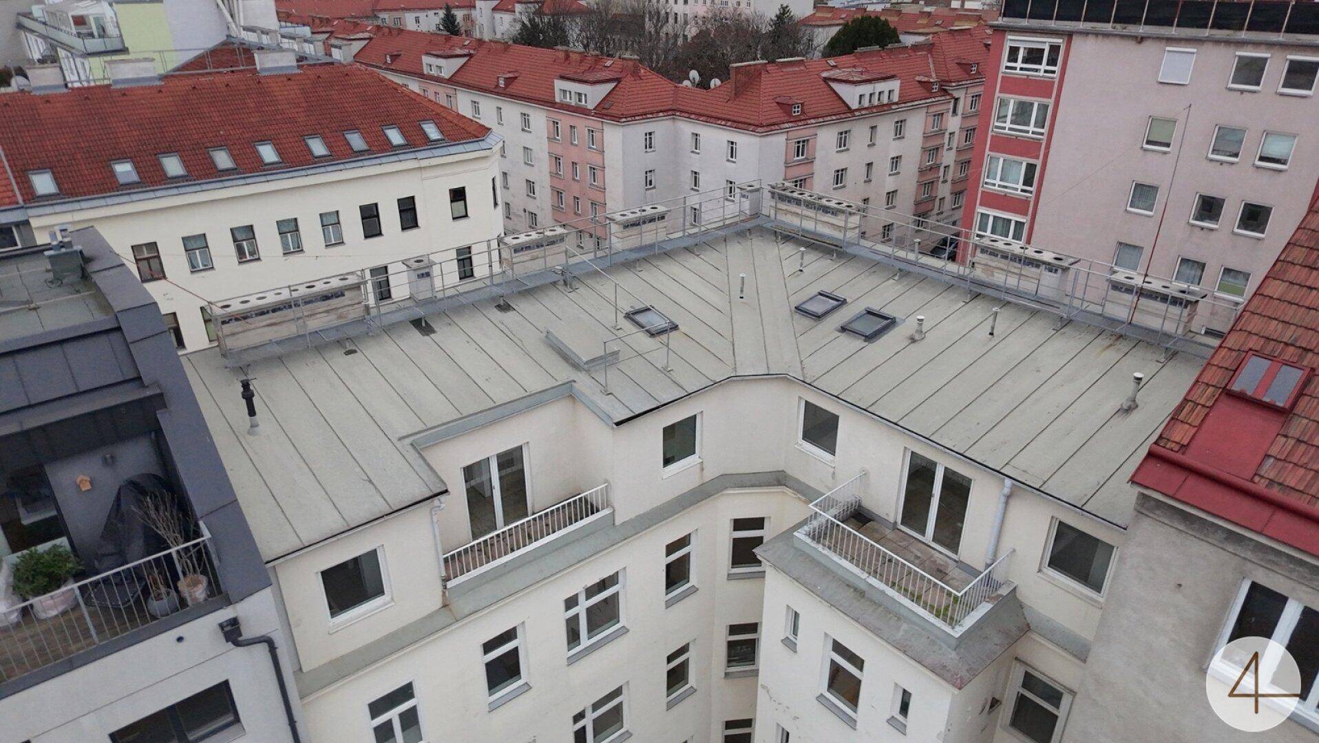 Dachansicht eines Wohngebäudes mit umliegenden Dächern und städtischer Bebauung.