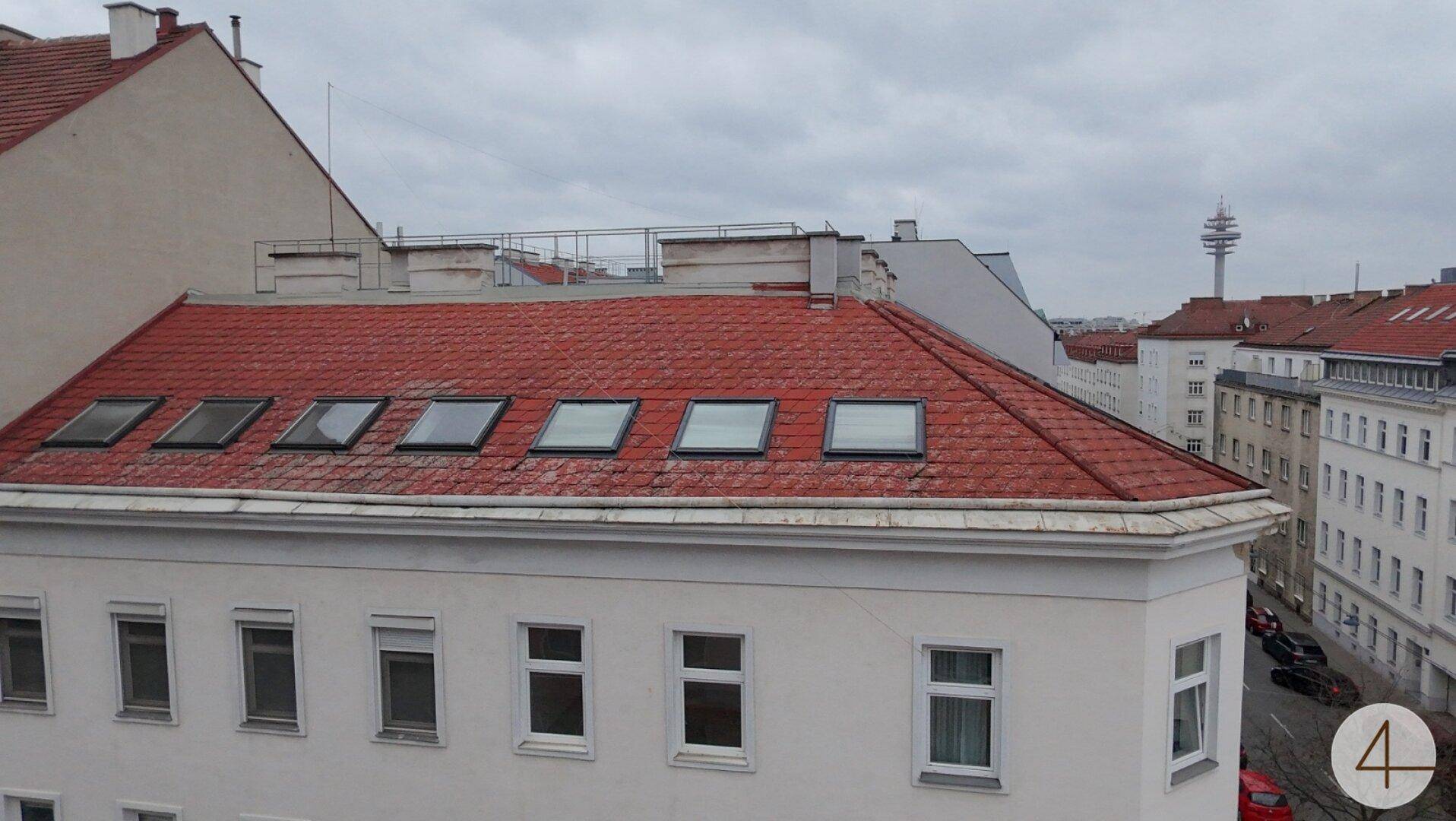 Dachansicht eines Gebäudes mit roten Ziegeln und mehreren Dachfenstern.