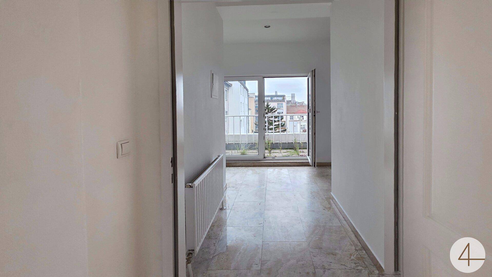 Heller Eingangsbereich mit Fliesenboden und direktem Zugang zu einem Balkon.