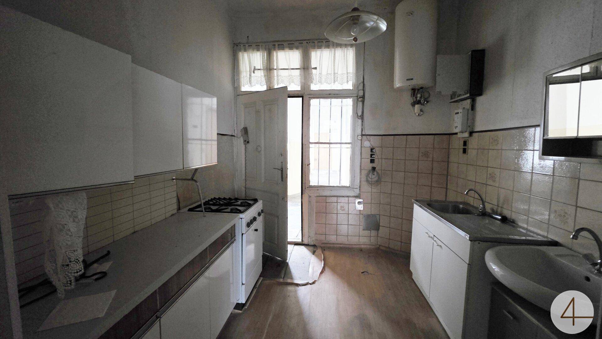 Funktionale Küche mit weißen Schränken, Gasherd und Fenster zum Hof.