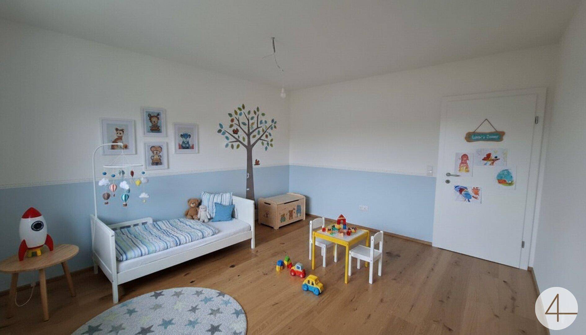 Freundliches Kinderzimmer mit Holzboden, Spielbereich und kindgerechter Wandgestaltung.