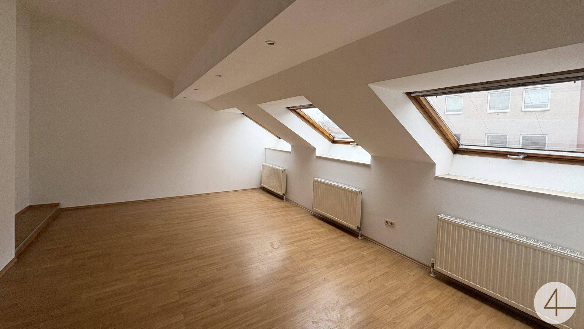 Heller Dachbodenraum mit Holzboden, Dachfenstern und Heizkörpern, bereit zur individuellen Gestaltung.
