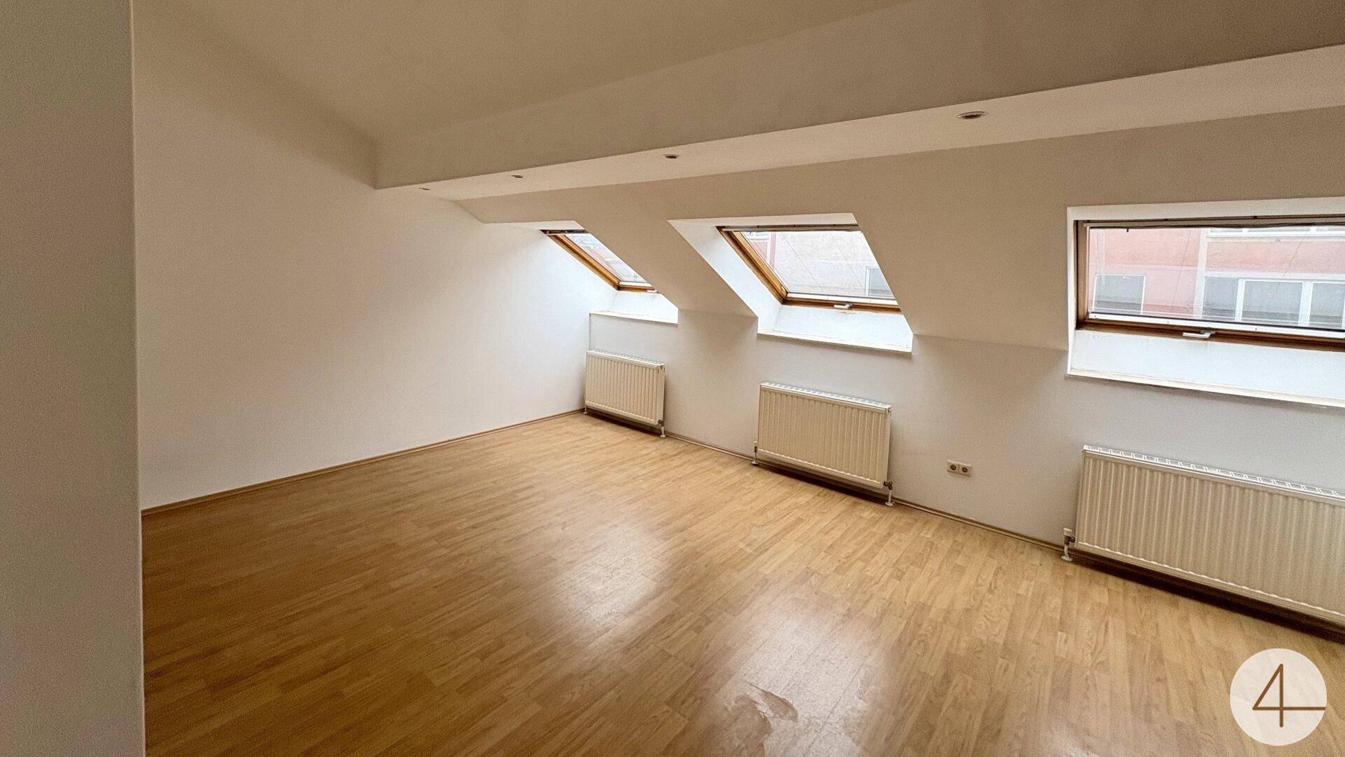 Geräumiges Dachgeschosszimmer mit mehreren Dachfenstern und hellem Holzboden.