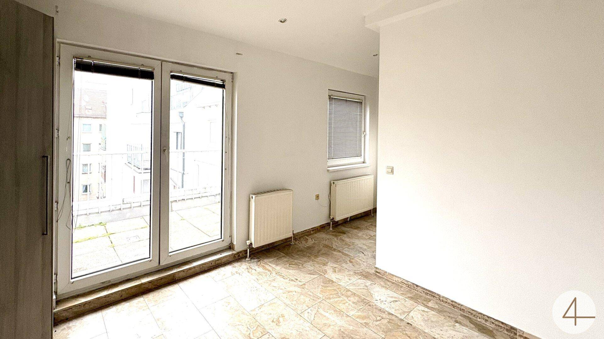 Lichtdurchfluteter Raum mit Fliesenboden und großen Fenstertüren zum Außenbereich.