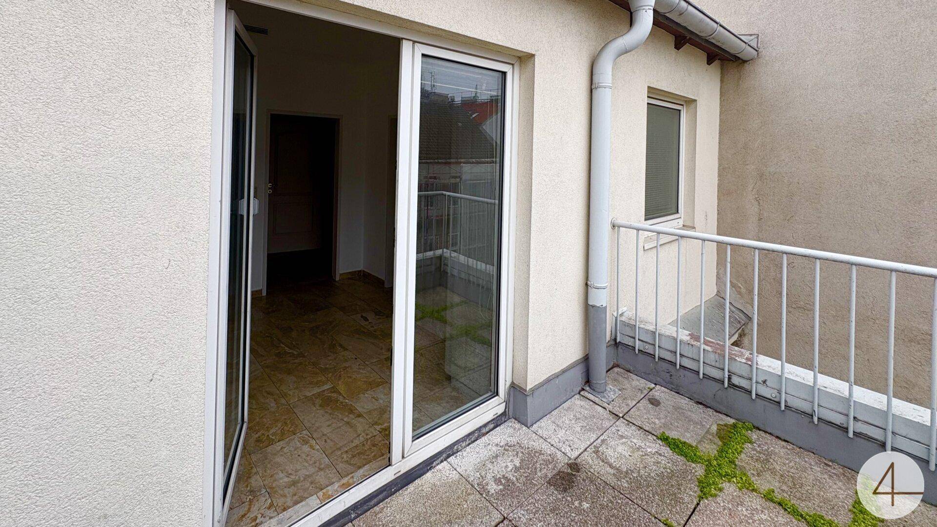 Kleine Terrasse mit Fliesenboden und Blick auf die umliegenden Gebäude.