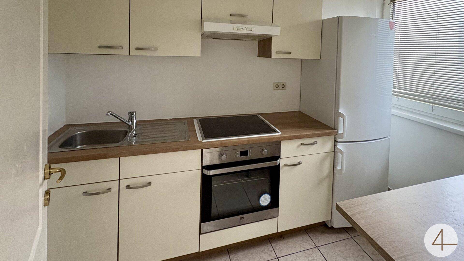 Funktionale Küchenzeile mit hellen Schränken, Herd, Backofen und Kühlschrank.